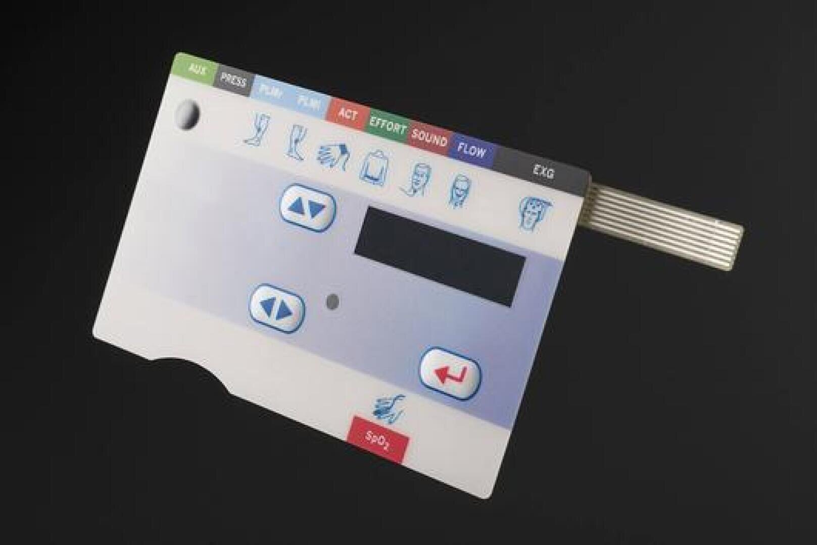 A flexible electronic control panel with buttons, symbols, and a small screen for a medical device, shown on a black background. The panel includes arrow keys and various labeled functional areas.