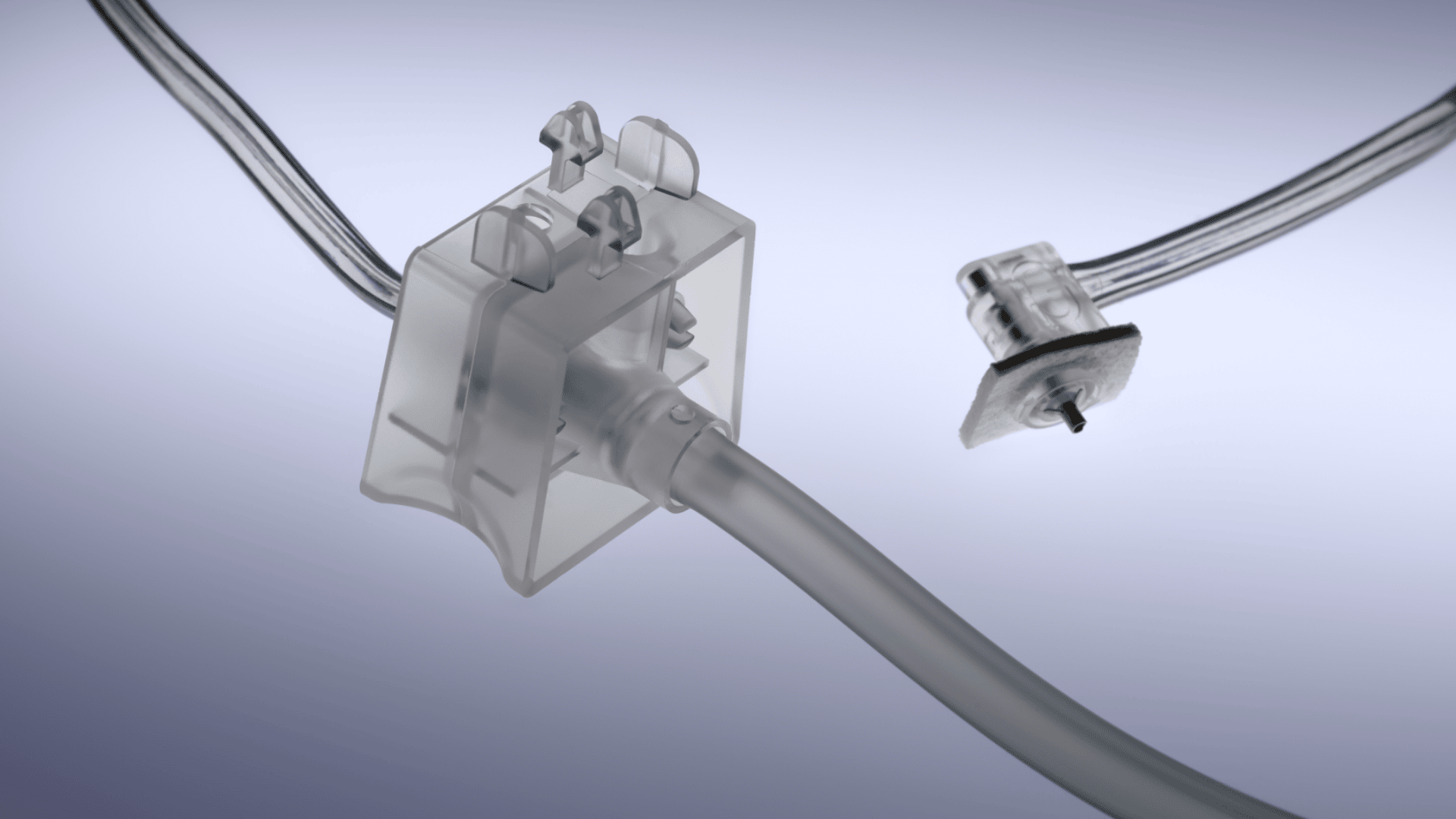 Nahaufnahme eines transparenten medizinischen Kunststoffkonnektors mit angeschlossenen Schläuchen, dargestellt auf einem hellvioletten Hintergrund. Daneben befindet sich ein weiterer Stecker mit Drähten, der noch nicht angeschlossen ist.
