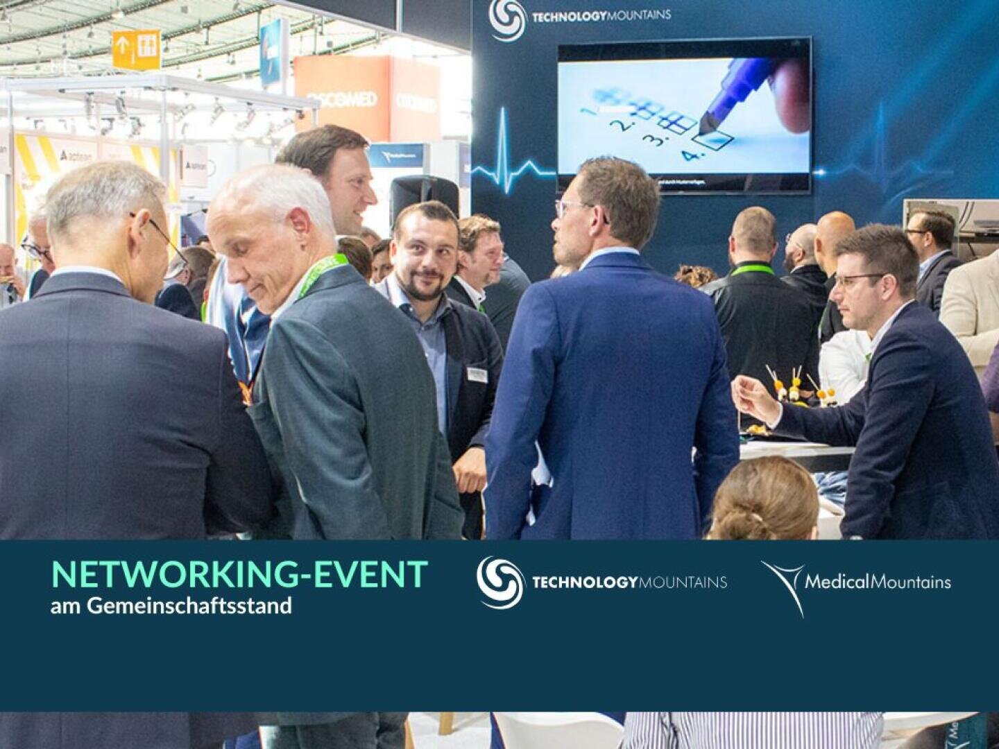 A group of people in business attire are chatting at a networking event. Above them is a screen with a heart rate graph and a hand writing on paper. Event branding and logos can be seen on a teal banner at the bottom.