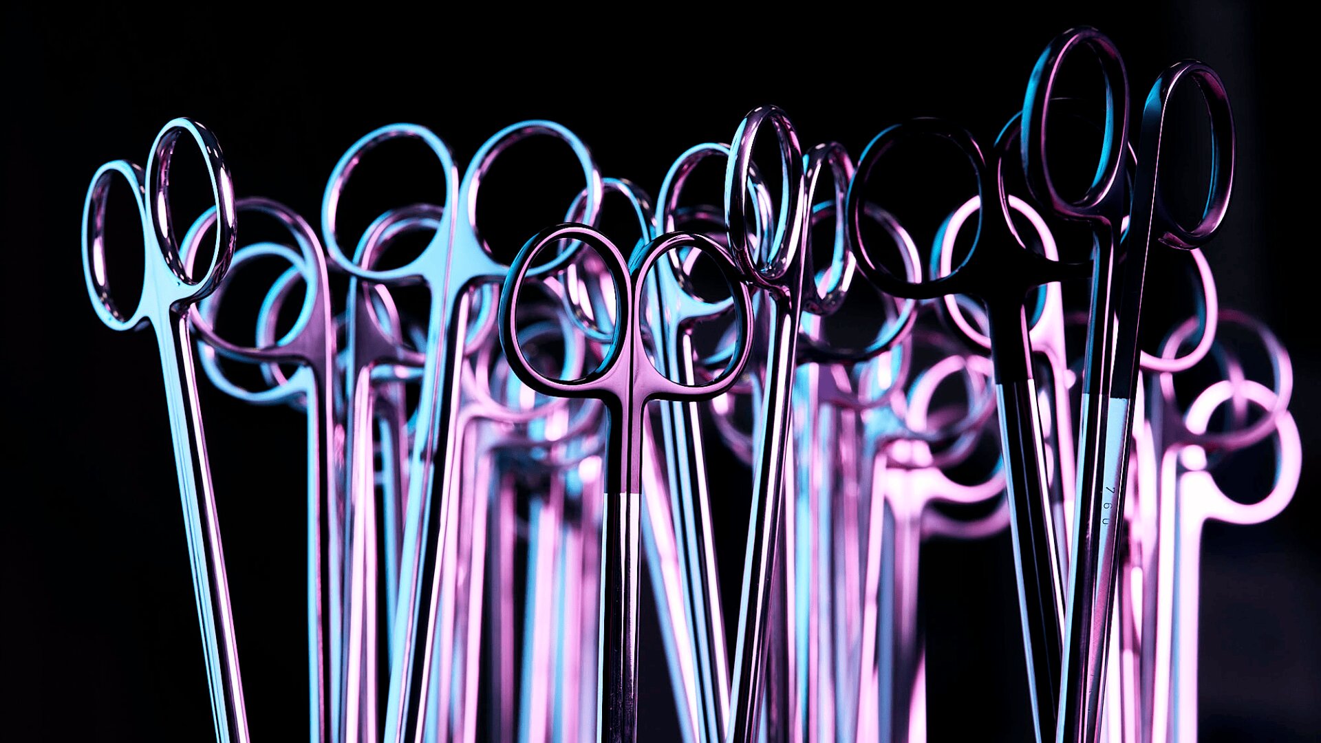 Eine Gruppe glänzender chirurgischer Scheren und Gefäßklemmen steht aufrecht vor einem schwarzen Hintergrund, der durch blaue und violette Beleuchtung einen metallischen, futuristischen Effekt erzeugt.