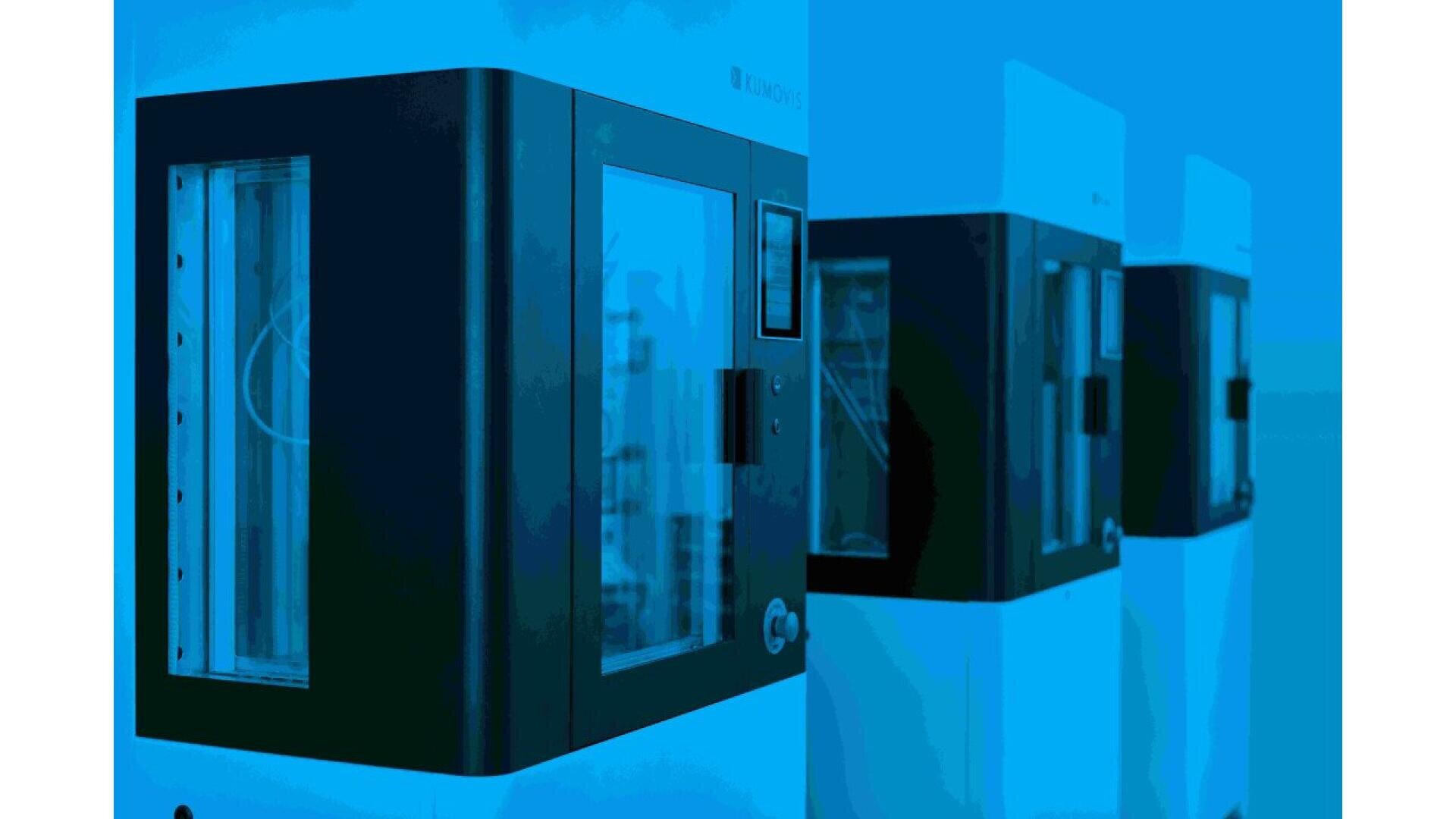 Three modern, rectangular laboratory machines with glass doors and black-and-white exteriors are lined up side by side against a blue background.
