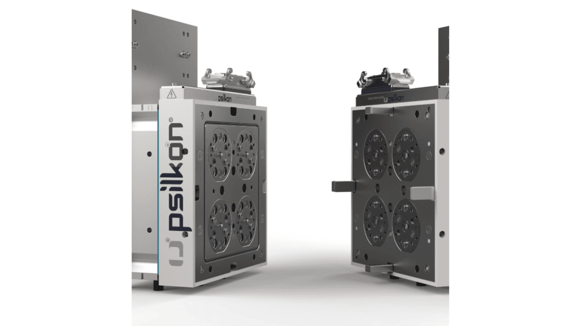 Two metallic mold tool components with multiple circular cavities are positioned upright and facing each other. The components are labeled psiikon and have sleek, industrial designs with bolts and handles visible.