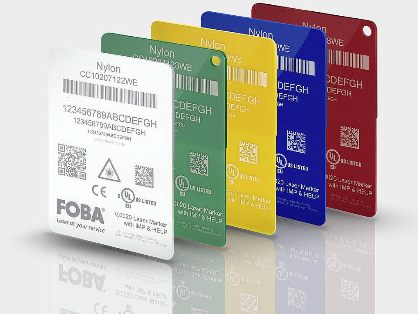 Five colored tags (white, green, yellow, blue, red) labeled “Nylon” are displayed standing upright. Each tag features serial numbers, QR codes, barcodes, and certification logos. The tags cast soft reflections below.