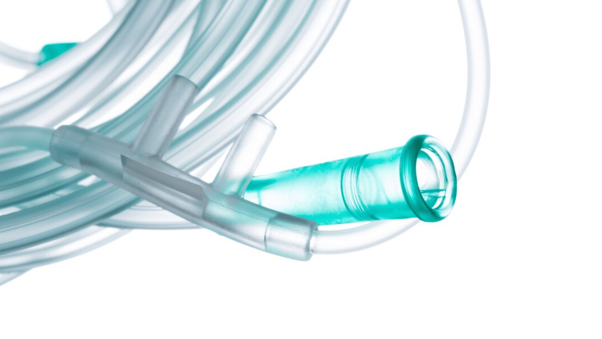 Close-up of a clear and teal oxygen nasal cannula tubing, coiled on a white background.