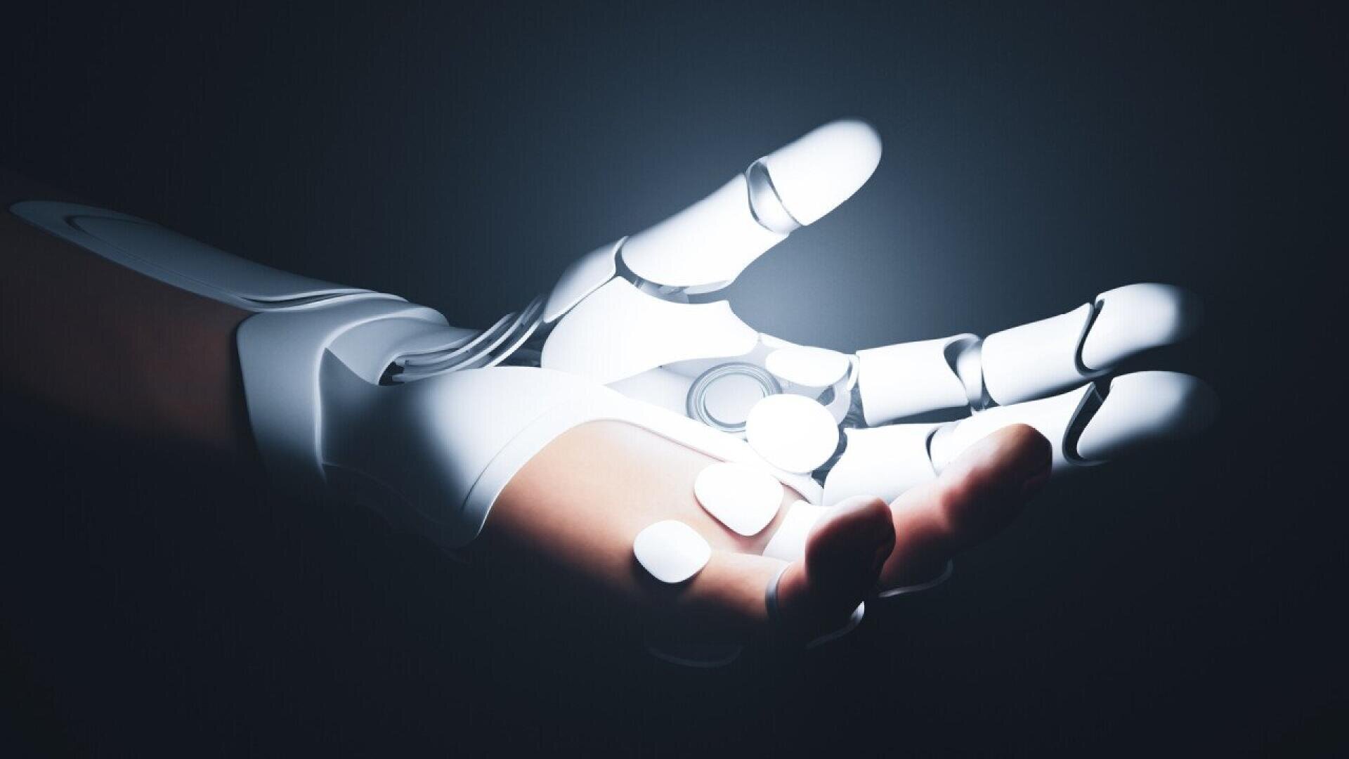 A robotic hand with sleek white and metallic surfaces is extended with open fingers, illuminated dramatically against a dark background, symbolizing advanced technology and artificial intelligence.
