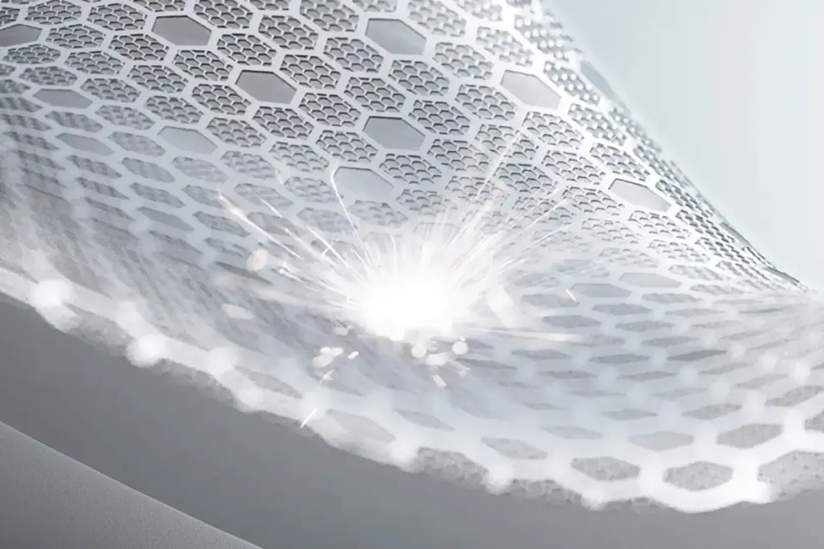 Close-up of a white, honeycomb-patterned surface being struck by a bright spark or burst of light, highlighting the structure and pattern.
