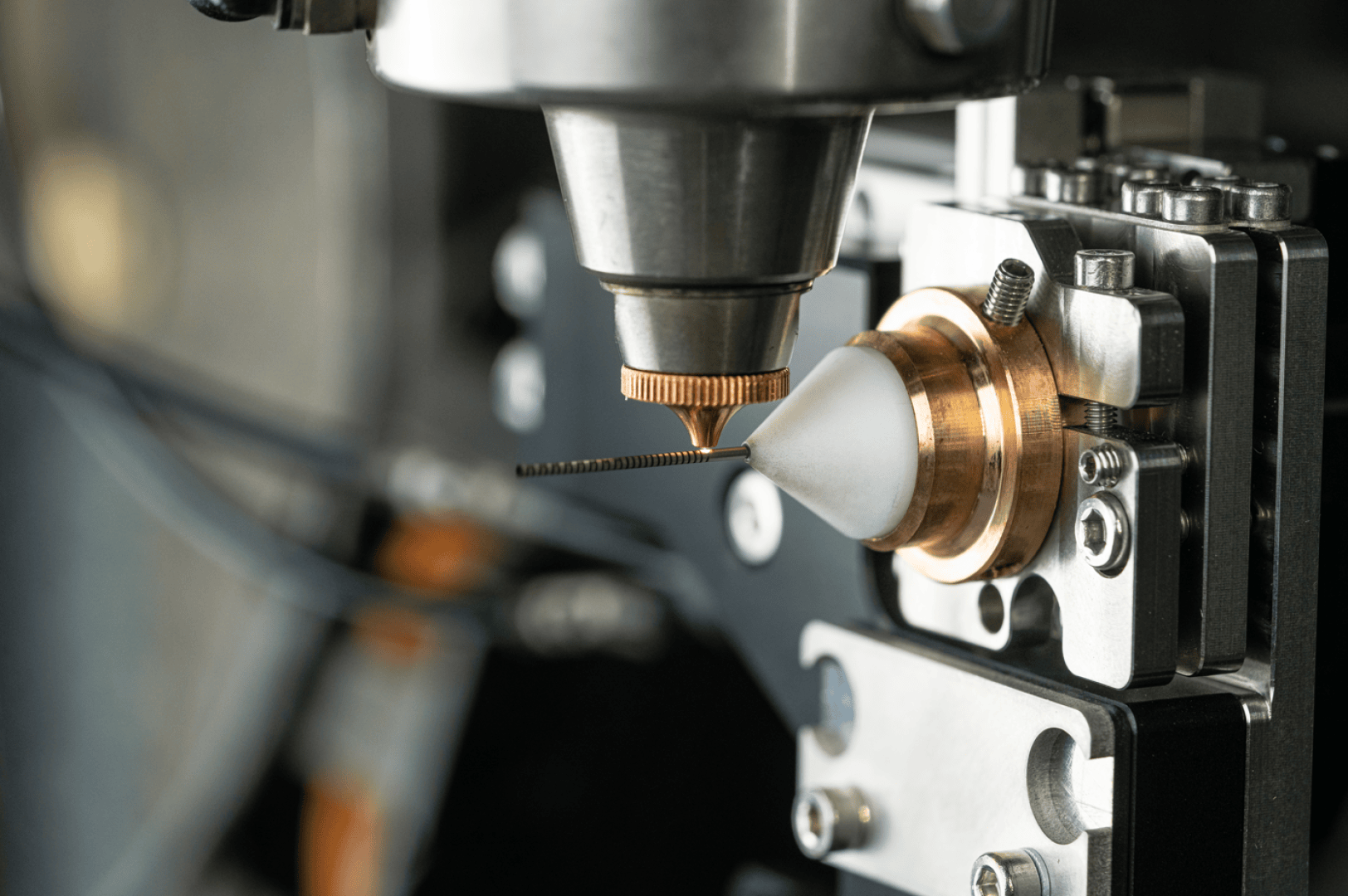 Nahaufnahme einer CNC-Maschine oder einer industriellen Bohrmaschine mit einem Präzisionswerkzeug (Bohrer), das in einer Metallhalterung montiert ist, wobei der Schwerpunkt auf den detaillierten mechanischen Komponenten und den reflektierenden Metalloberflächen liegt.