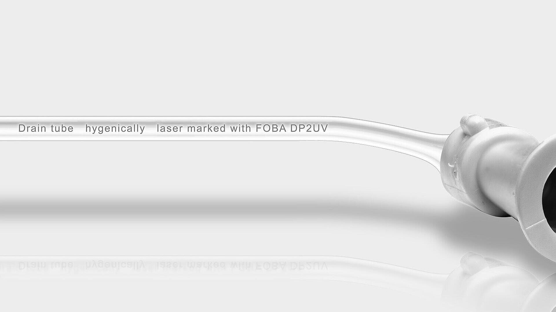 Transparentes Drainagerohr mit seitlich aufgedrucktem Text Drainagerohr hygienisch lasermarkiert mit FOBA DP2UV auf sauberem, weissem Hintergrund.