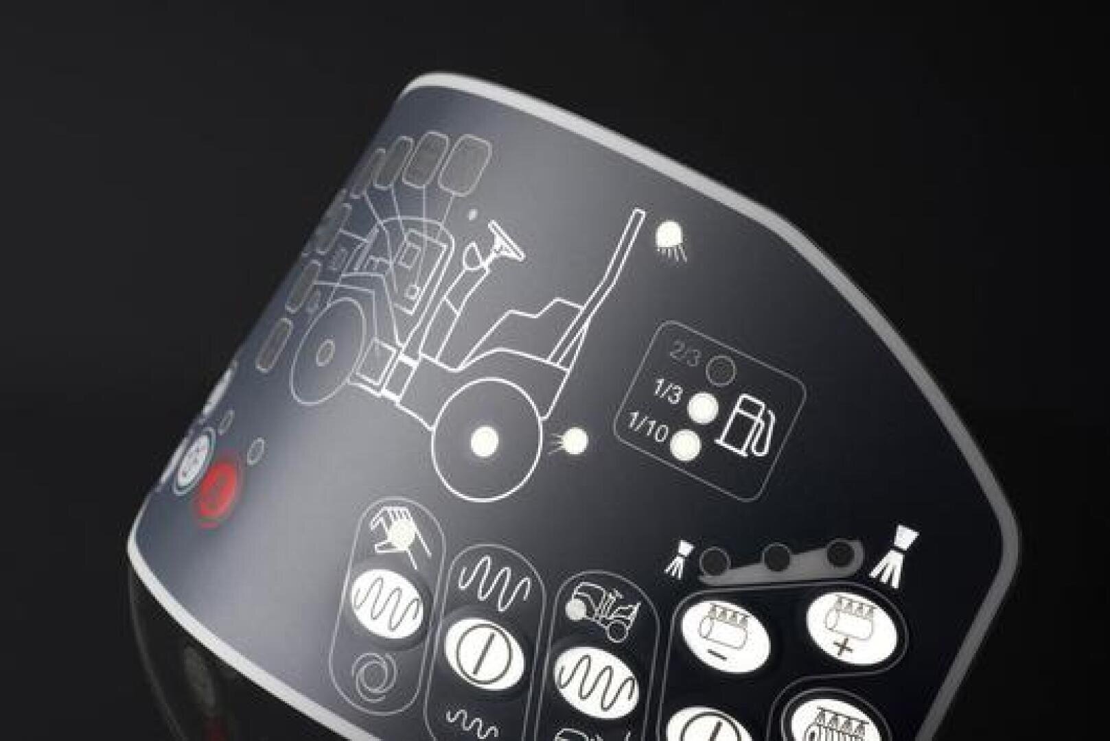 Curved control panel with white symbols, including a tractor illustration, buttons, and indicator lights on a dark background, showing machine operating settings.
