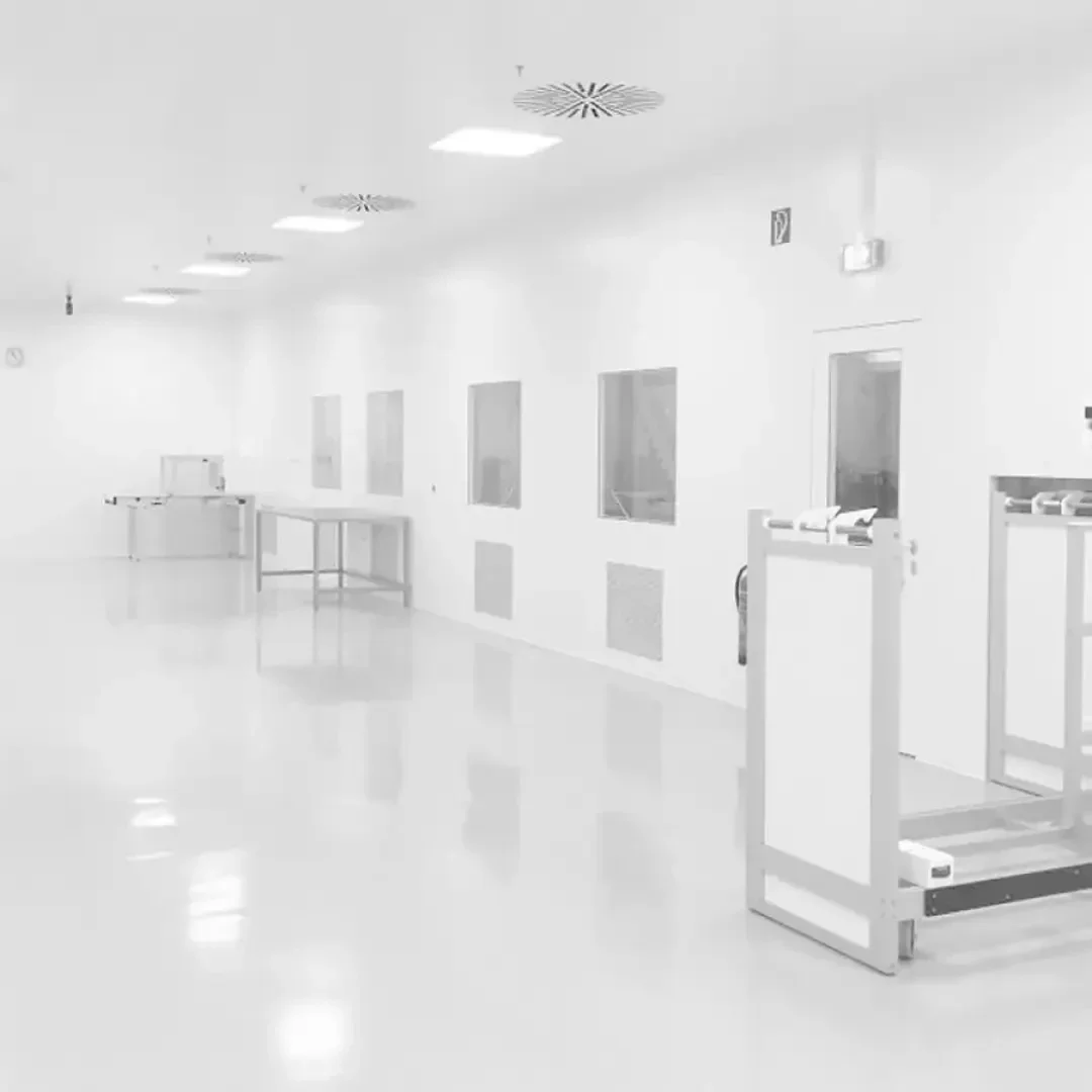 Ein heller, sauberer, leerer Raum mit weißen Wänden, glänzenden Böden, mehreren Fenstern, Tischen und Geräten, der einer Labor- oder Reinraumumgebung ähnelt.