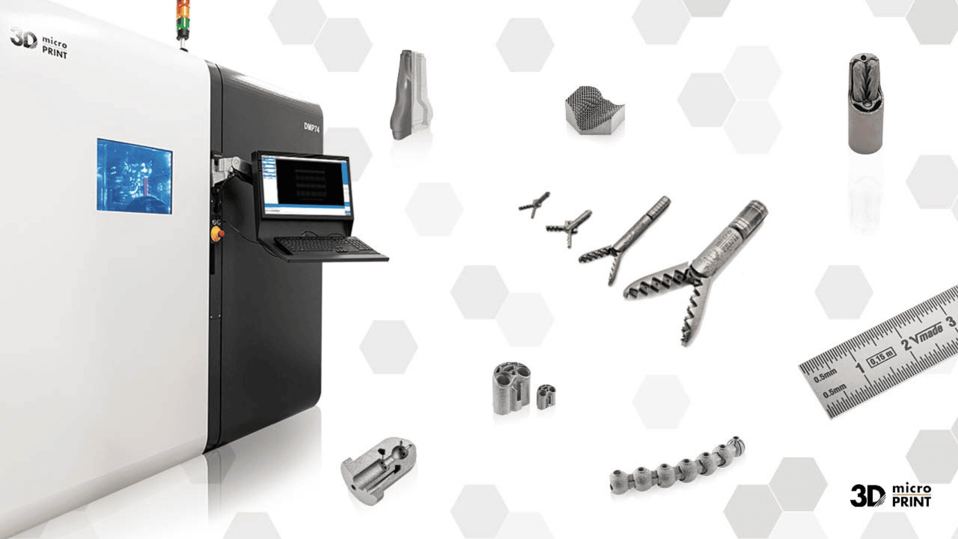 Ein industrieller 3D-Drucker mit einem Monitor und mehreren kleinen, metallischen 3D-gedruckten Bauteilen in der Nähe; ein Lineal und Sechseckmuster erscheinen im Hintergrund. Das Logo von 3D Micro Print befindet sich in der unteren rechten Ecke.
