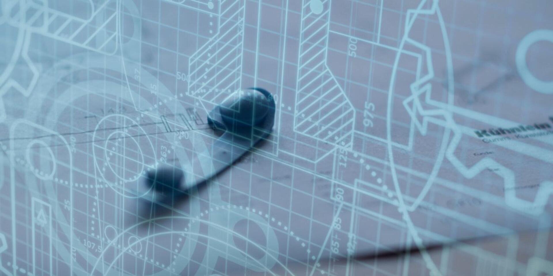 Black headphones lying on a surface covered with transparent technical drawings, blueprints, and mechanical diagrams, connecting elements of technology and engineering.