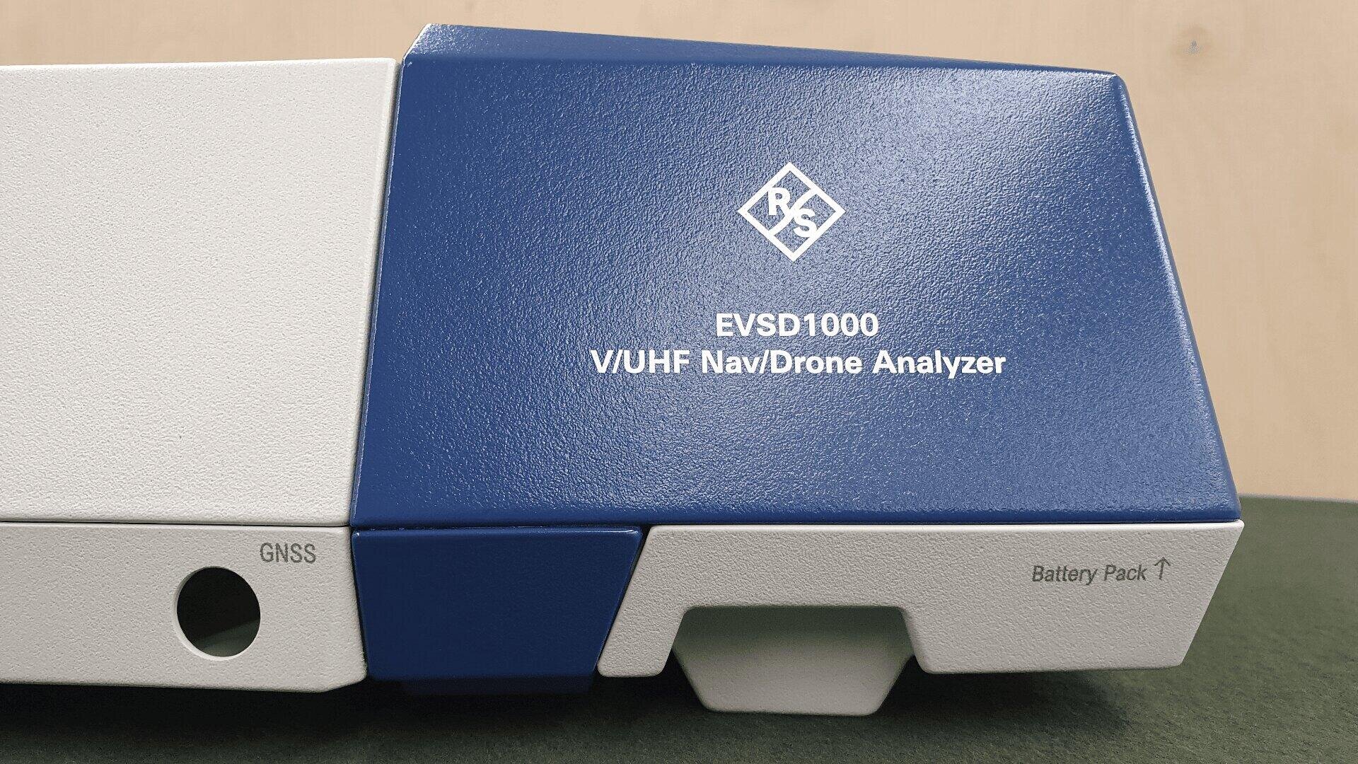 Nahaufnahme eines blau-weißen Geräts mit der Aufschrift EVSD1000 V/UHF Nav/Drone Analyzer mit dem R&S-Logo und beschrifteten Anschlüssen für GNSS und Battery Pack.
