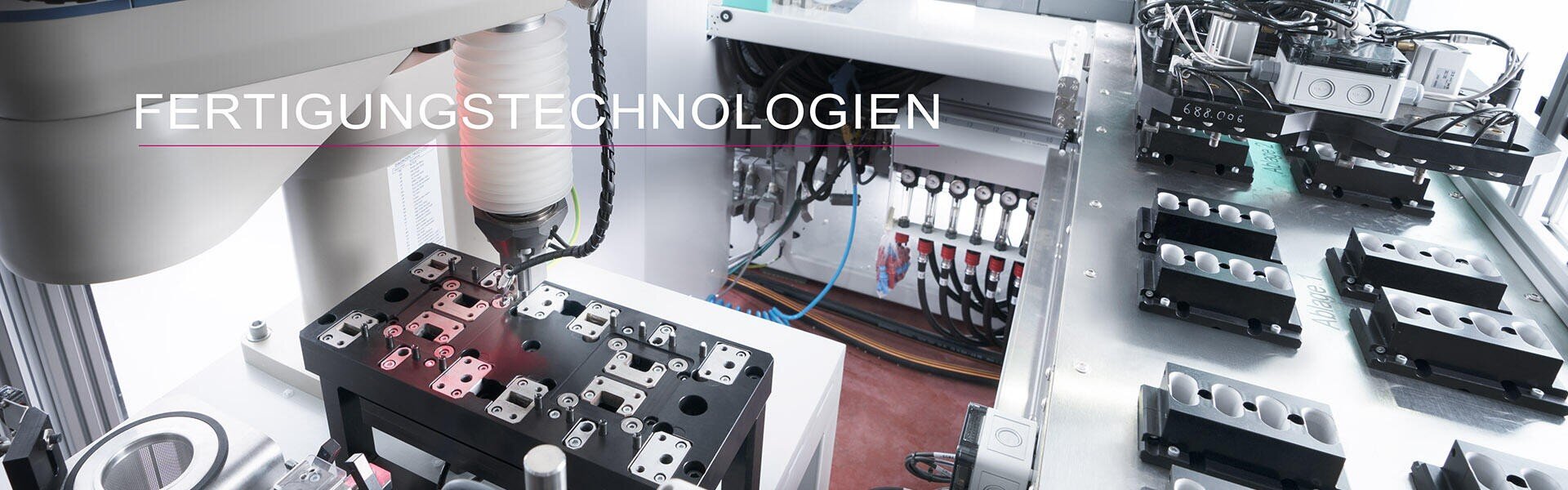Nahaufnahme einer automatisierten Fertigungsanlage mit Roboterarmen und Präzisionsmaschinen für die Montage von Bauteilen. Das deutsche Wort "FERTIGUNGSTECHNOLOGIEN" ist im oberen Bereich eingeblendet.