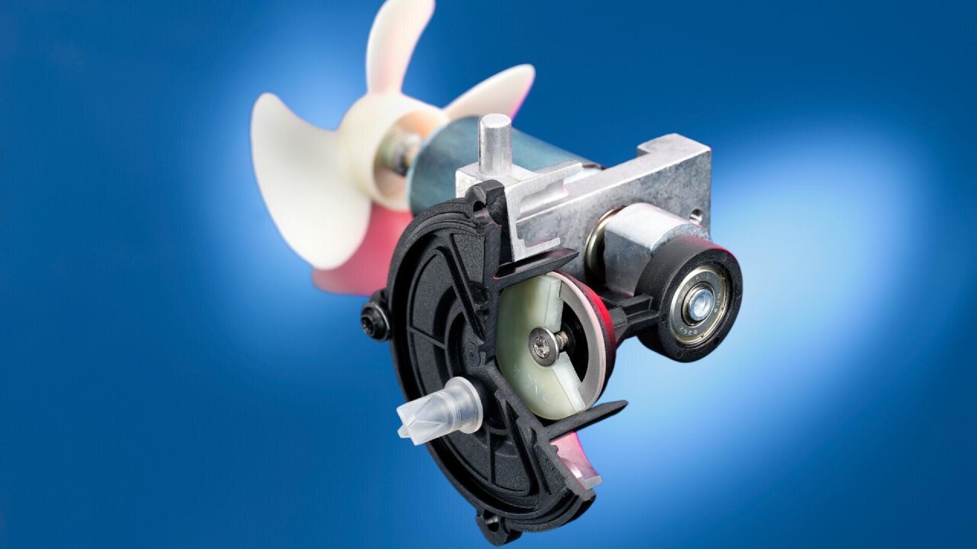 A close-up of a mechanical component featuring a plastic propeller and a small electric motor, set against a blue gradient background.