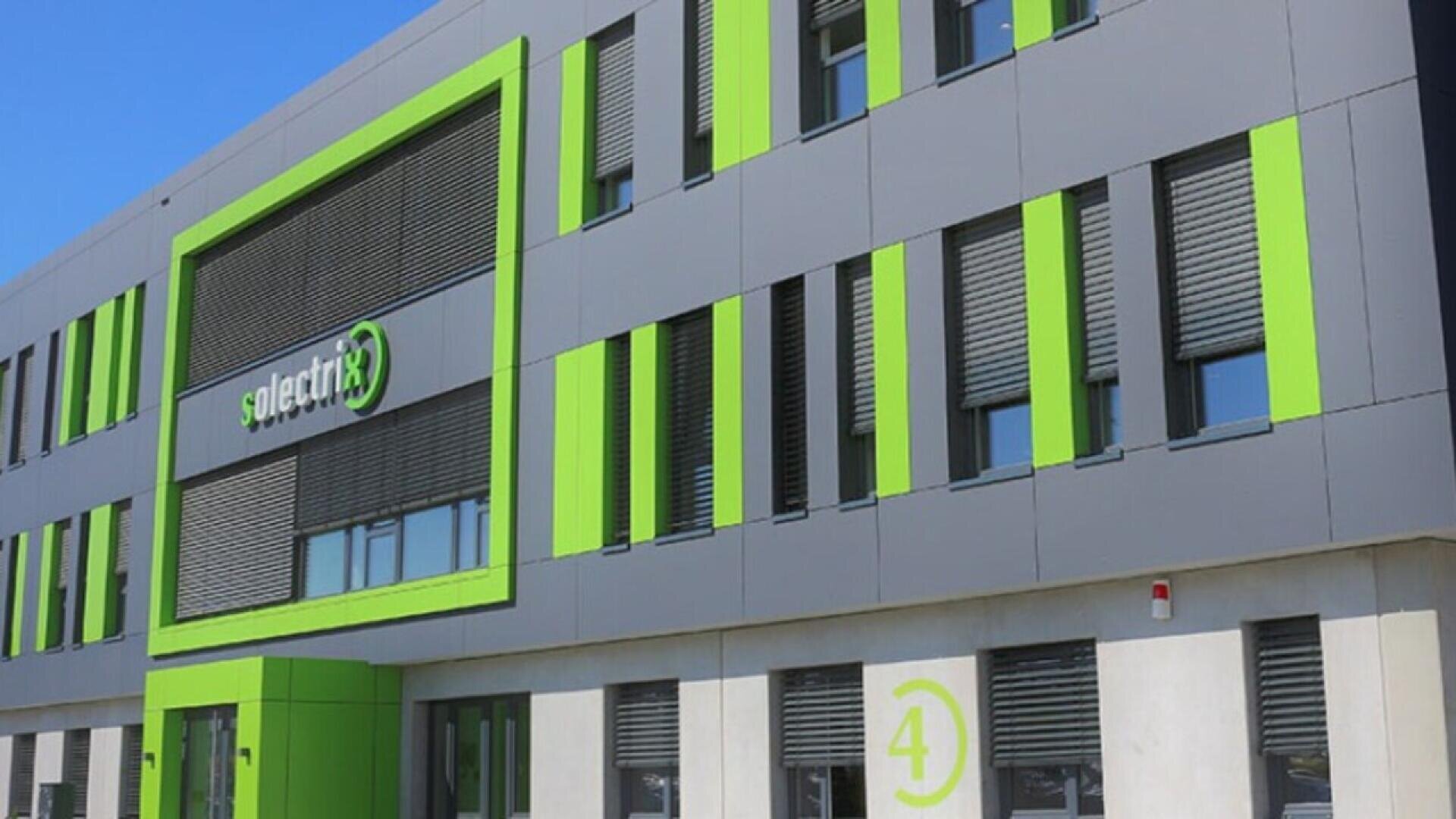 Modern gray building with green accents and the solectrix logo displayed above large windows; the number 4 is visible near the entrance on a white wall.