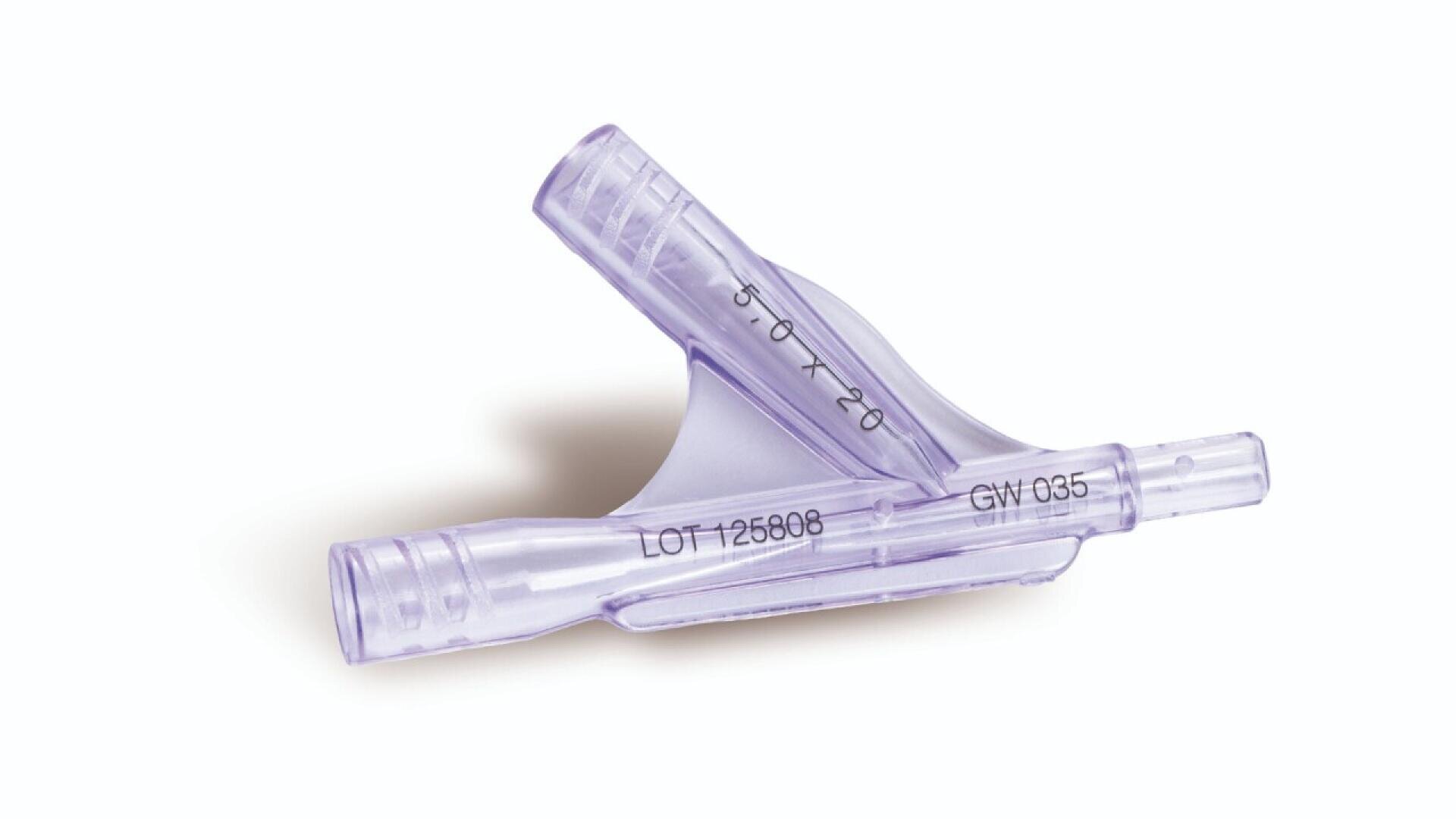 A clear, light purple Y-shaped medical connector with measurement markings and lot numbers printed on its surface, displayed on a white background.
