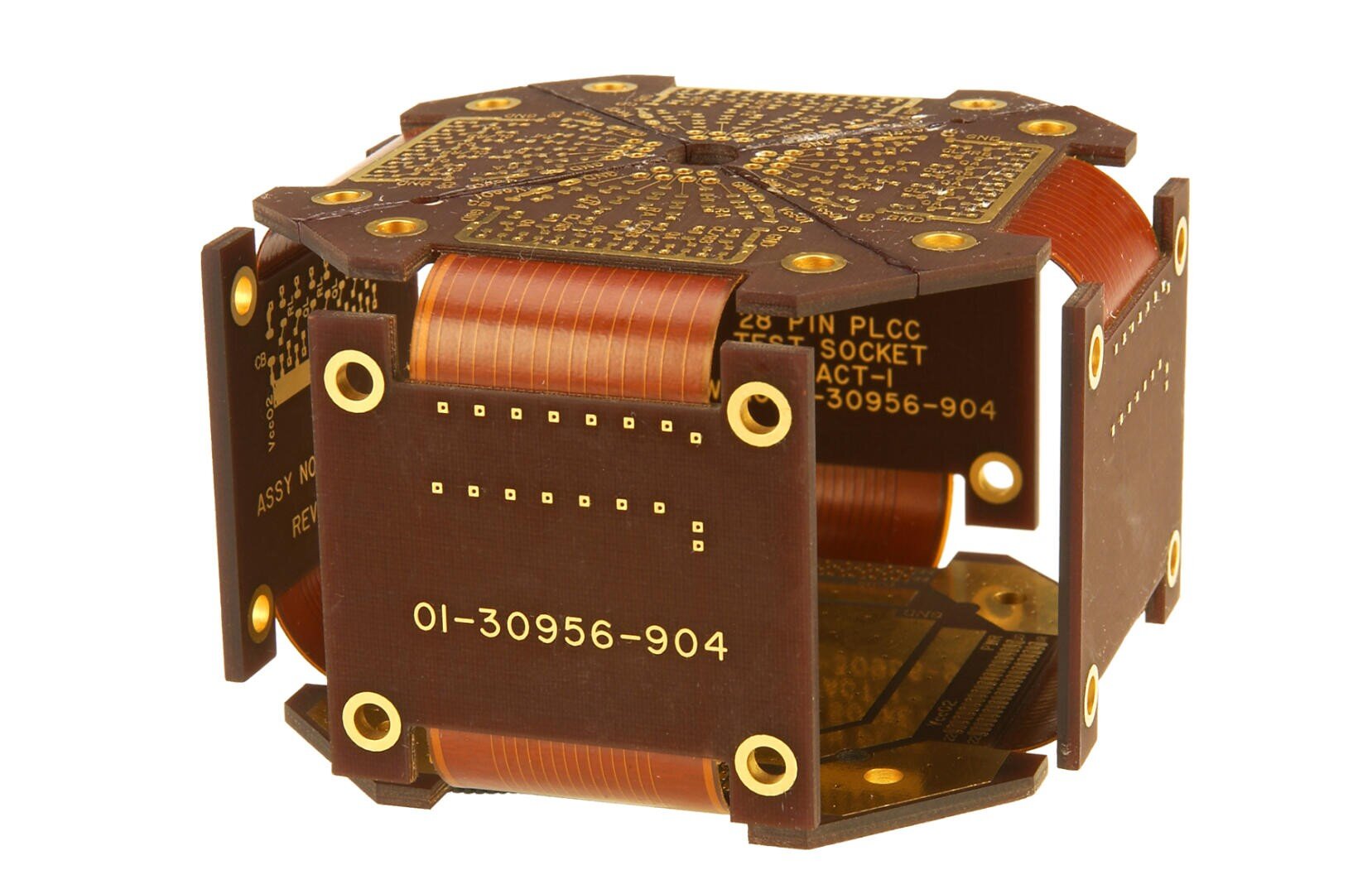 A close-up of a brown electronic component with gold connectors, labeled 26 PIN PLCC TEST SOCKET and 01-30956-904, featuring flexible ribbon-like structures and circuit board patterns.