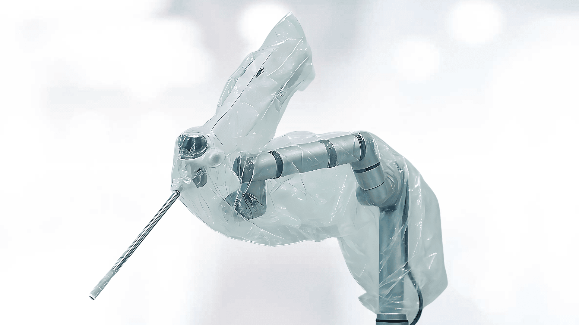 A robotic surgical arm covered with a sterile plastic drape, with a thin metal instrument protruding from the end, against a blurred white background.