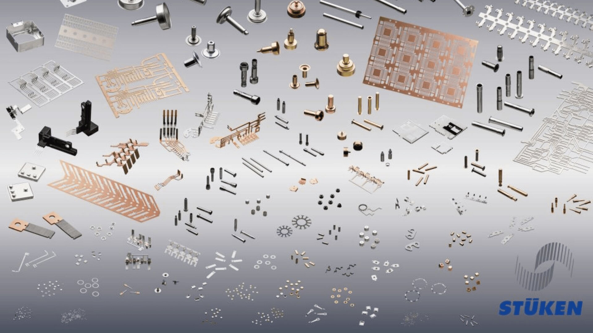Auf einem Hintergrund mit Farbverlauf ist eine große Auswahl an kleinen Präzisionsteilen und Komponenten aus Metall und Kunststoff angeordnet, mit dem STÜKEN-Logo in der unteren rechten Ecke.