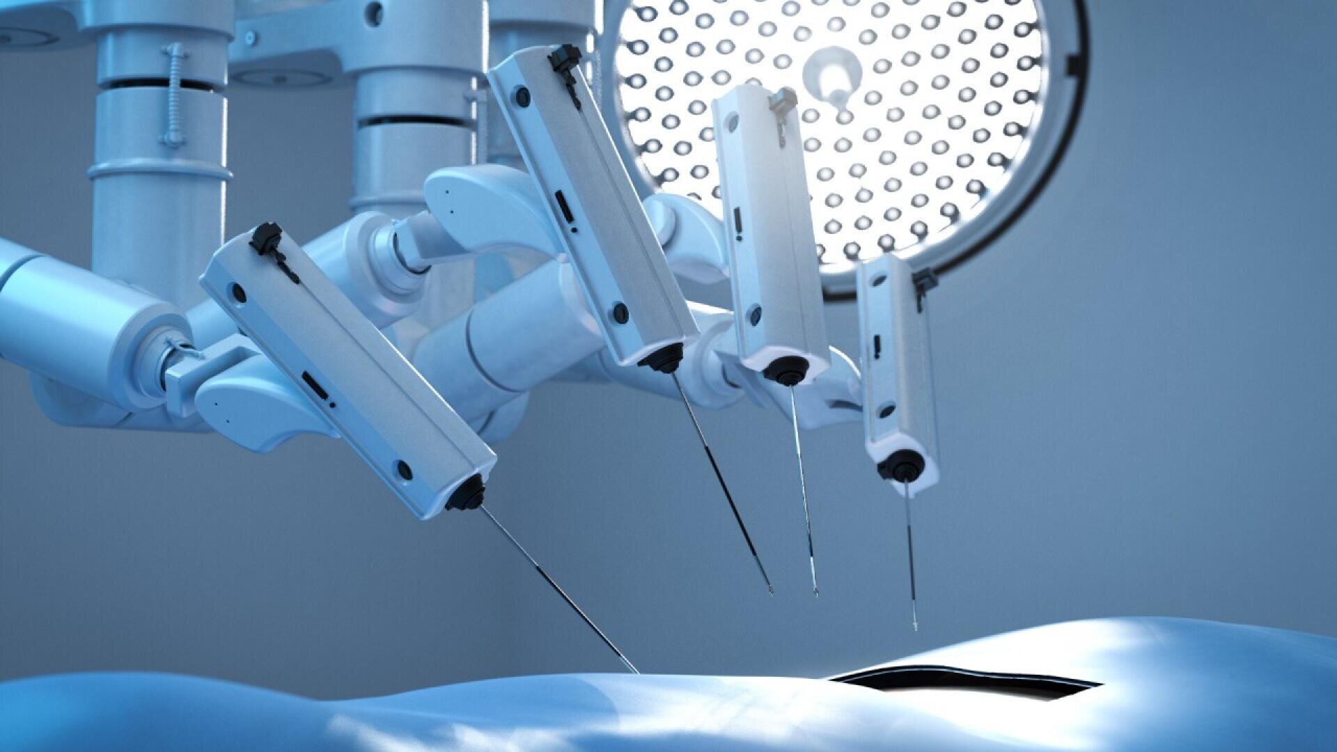 A close-up of robotic surgical arms performing a procedure on a patient under bright operating room lights, highlighting advanced medical technology in use.