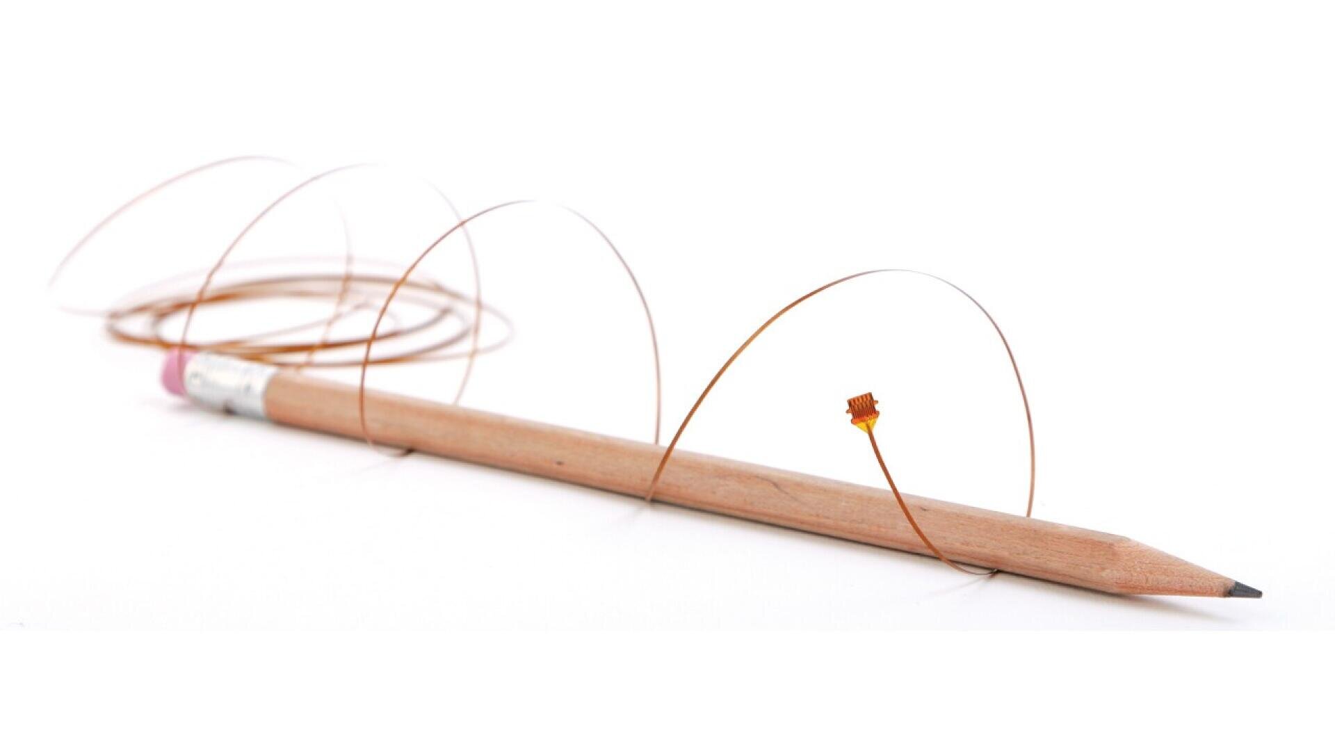 Ein horizontal liegender Holzstift, um den ein dünner, gewickelter Draht gewickelt ist und an dem ein kleines orangefarbenes Bauteil befestigt ist, alles auf einem weißen Hintergrund.