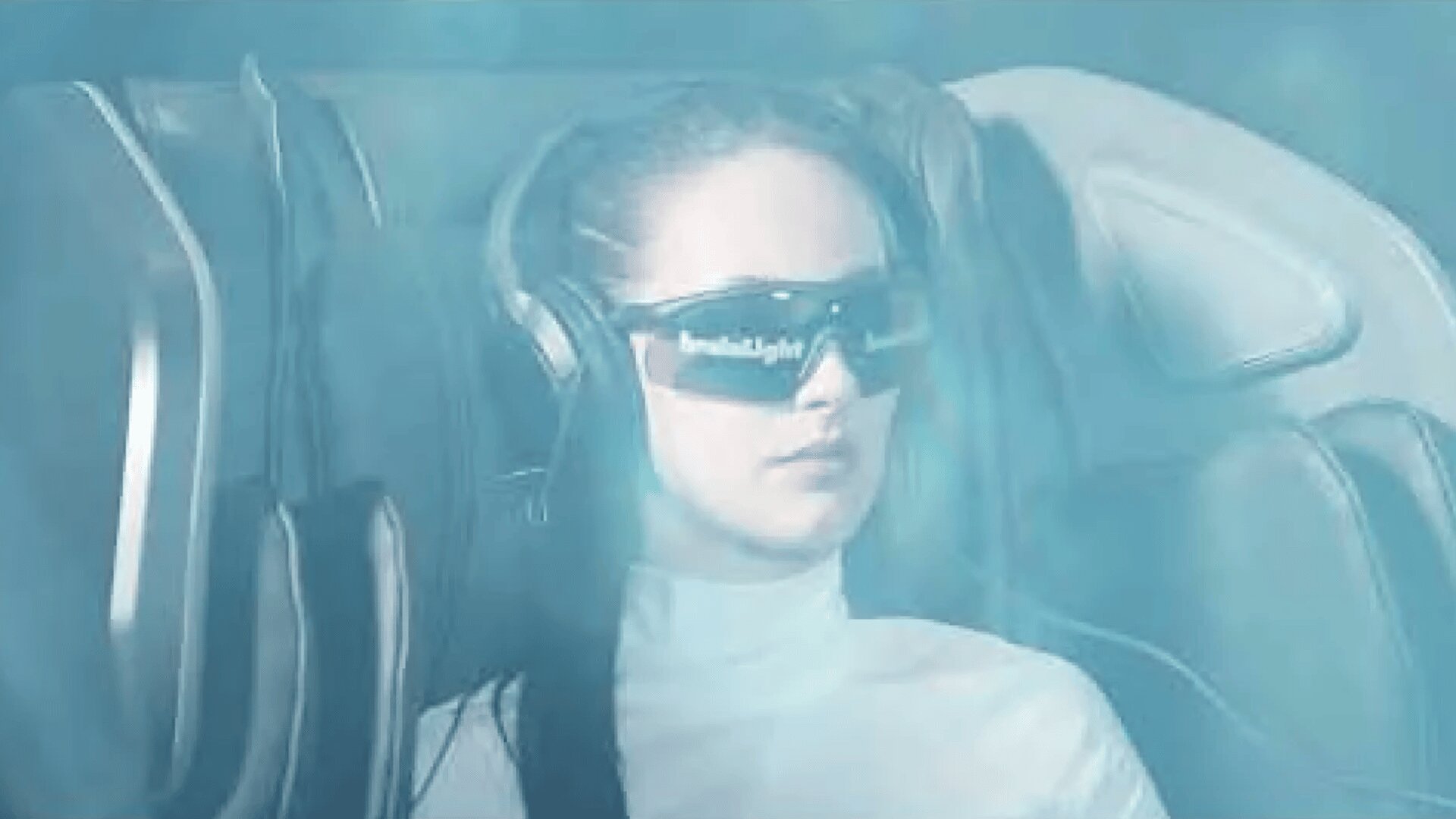 Eine Frau mit futuristischer Sonnenbrille und Kopfhörern sitzt in einem Hightech-Stuhl, der in blaues Licht getaucht ist und an eine Science-Fiction- oder Virtual-Reality-Kulisse erinnert.