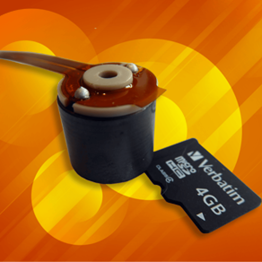 Eine schwarze microSD-Karte mit der Aufschrift „Verbatim 4GB“ neben einer kleinen zylindrischen elektronischen Komponente mit Kabeln, vor einem orangefarbenen Hintergrund mit kreisförmigen Mustern.