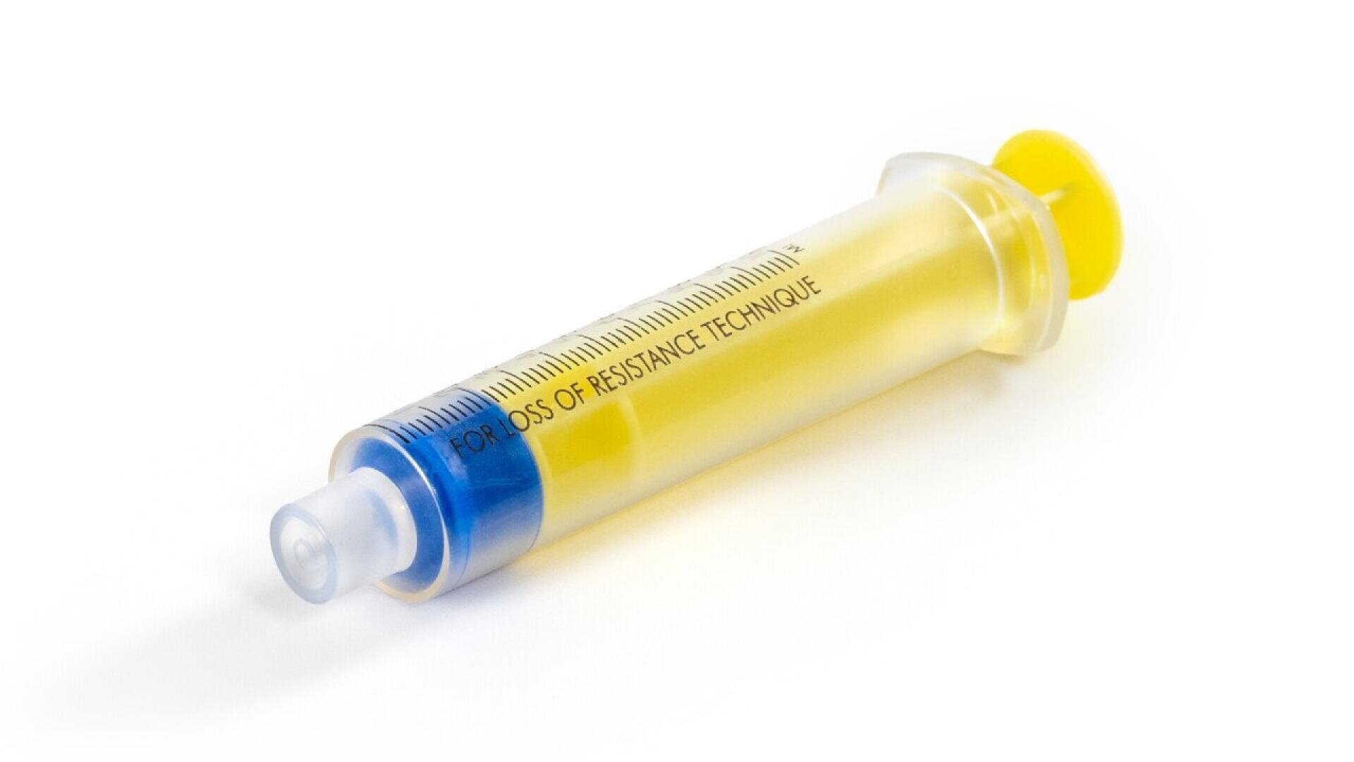 A close-up of a syringe filled with yellow liquid, labeled FOR LOSS OF RESISTANCE TECHNIQUE, with a blue tip and a yellow plunger, placed on a white background.
