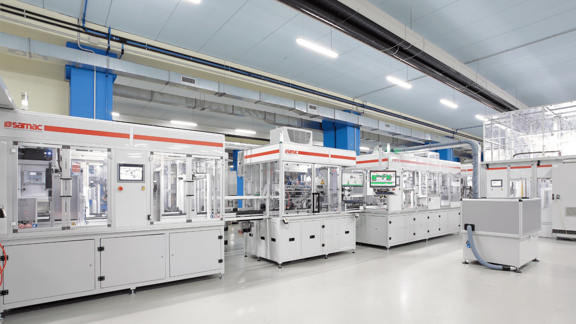 A clean, modern factory floor with advanced, automated machinery and equipment, white cabinets and control panels under bright overhead lighting, creating a high-tech industrial environment.
