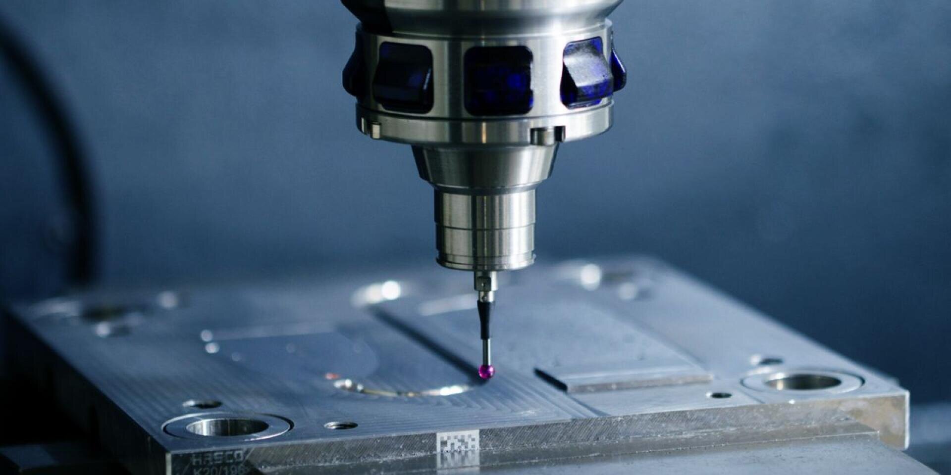 Close-up of a CNC machine tool with a precision measuring probe positioned over a metallic workpiece in an industrial environment.