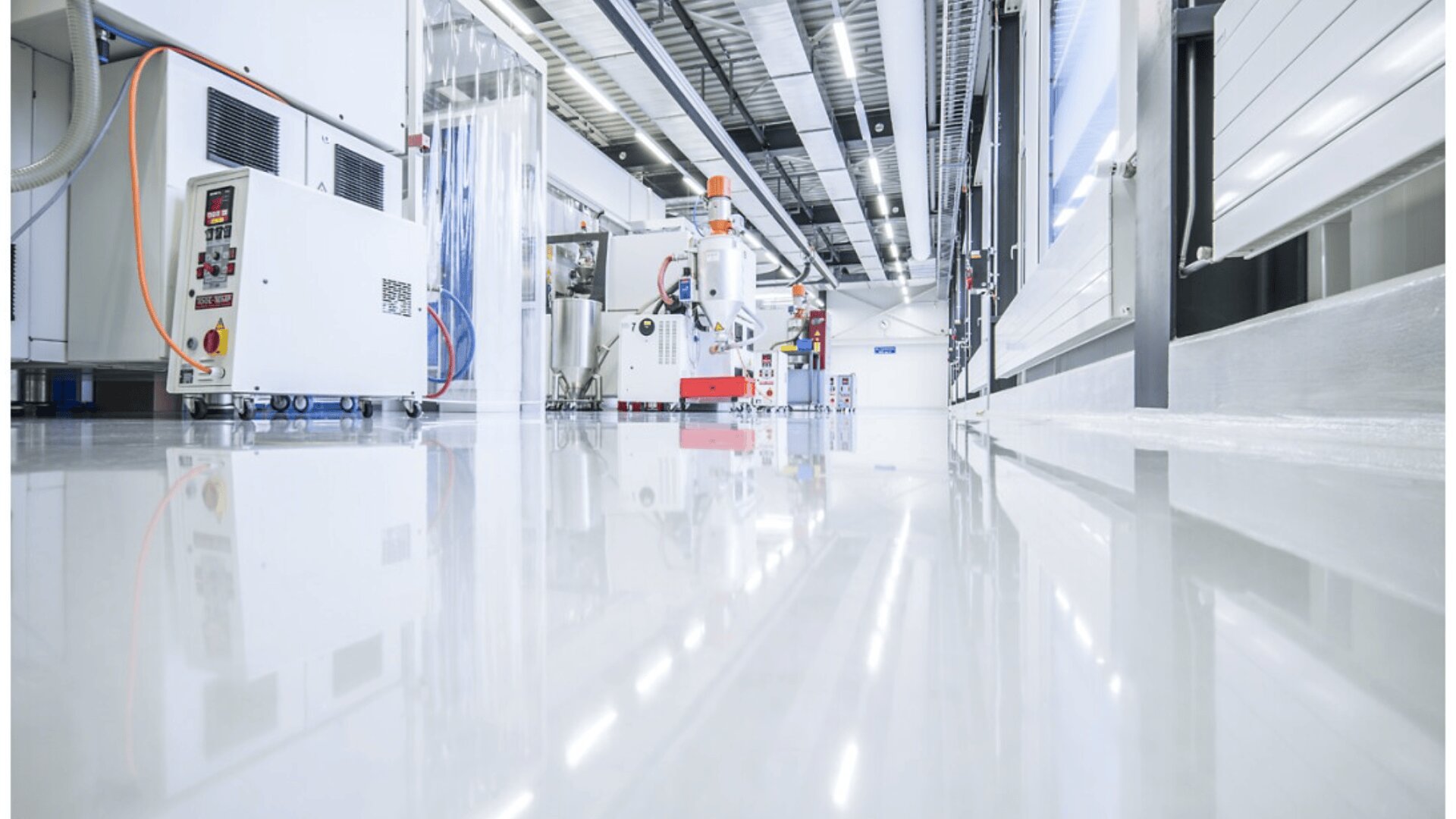 A clean, modern industrial facility with polished floors, bright lighting, and advanced machinery, including control panels and equipment, arranged along the spacious production area.