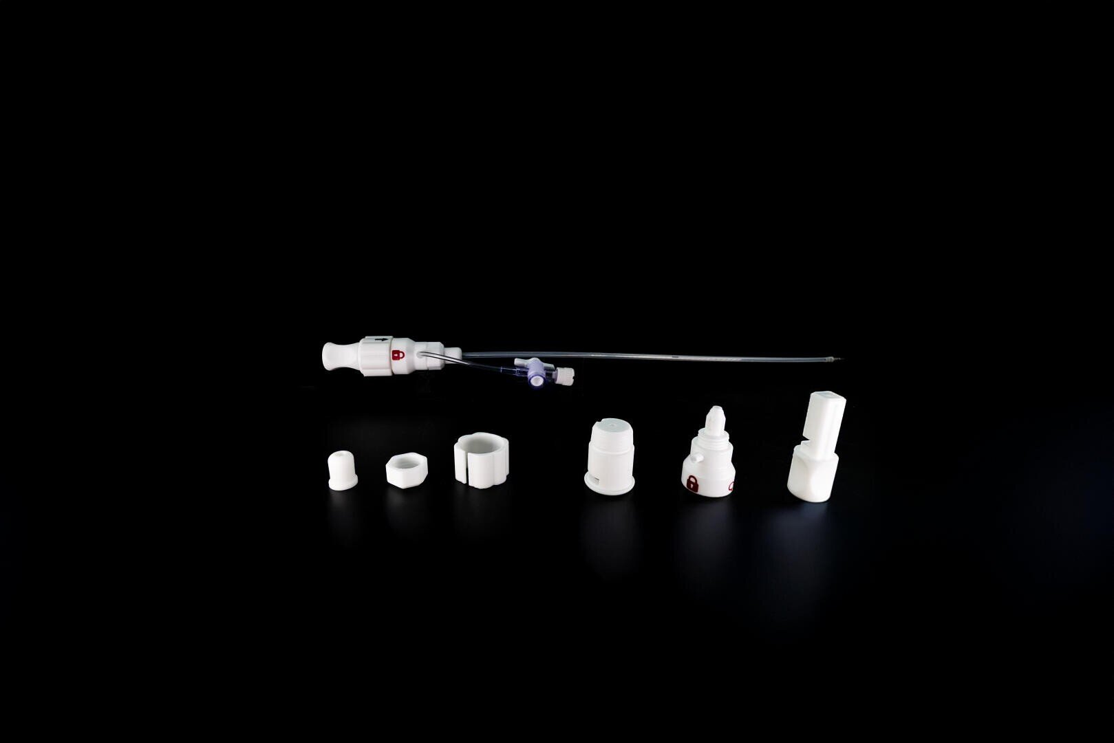 Eine Reihe weißer medizinischer Komponenten, darunter ein langes Instrument mit einem Griff und mehreren zylindrischen Aufsätzen, sind in einer Reihe auf einem schwarzen Hintergrund angeordnet.