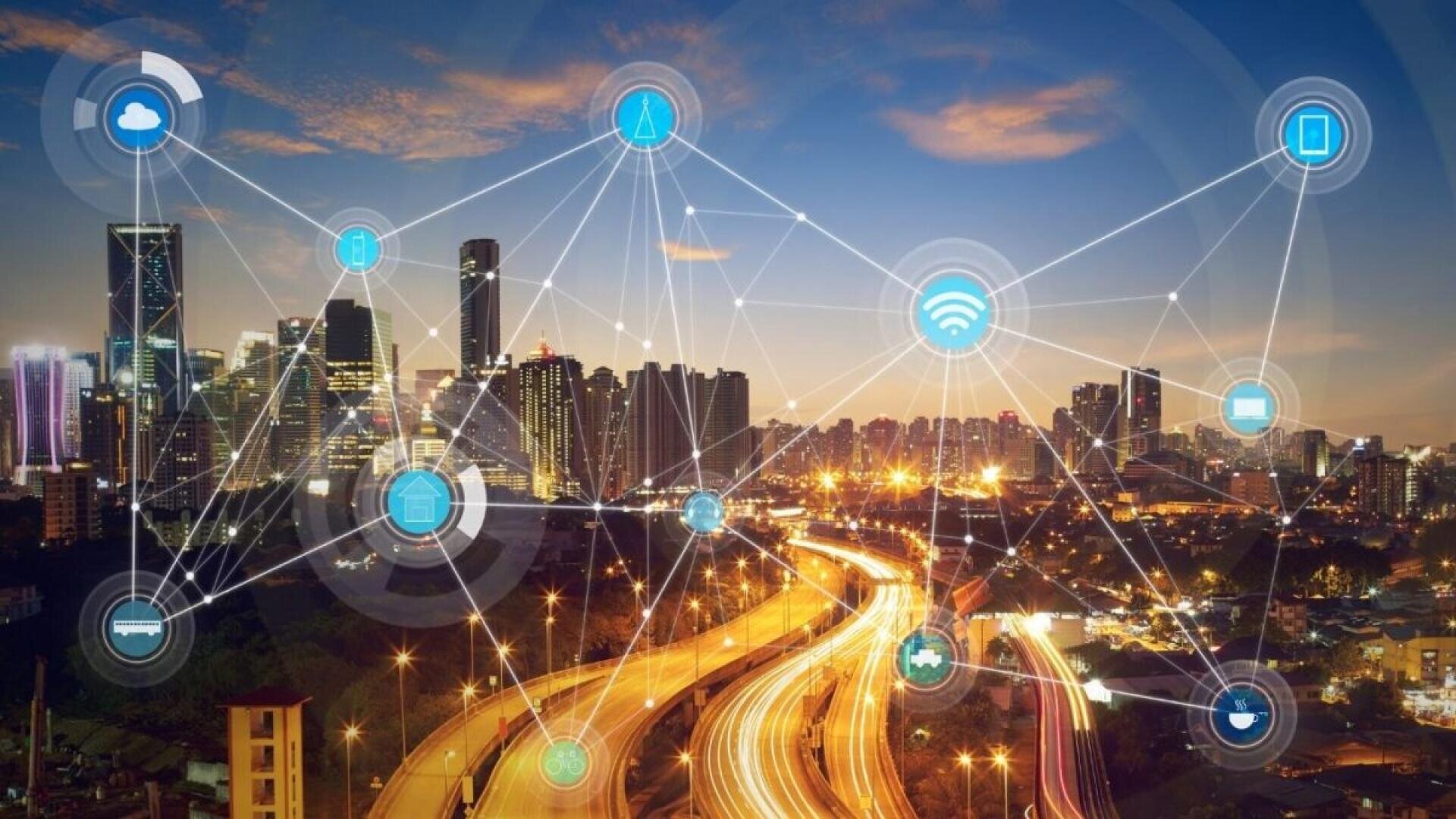 A city skyline at dusk with illuminated buildings and streets, overlaid with digital network symbols and connection lines representing smart city technology and connectivity.