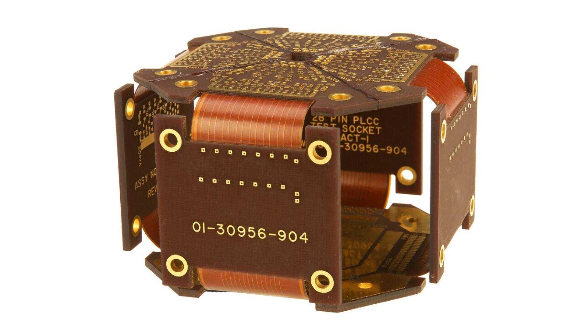 Ein braun-goldenes elektronisches Bauteil mit mehreren Flachbandkabeln, die zwischen sechs Leiterplatten verbunden sind und eine Würfelform bilden. Auf den Oberflächen sind goldene Anschlüsse und kleine Löcher sichtbar.