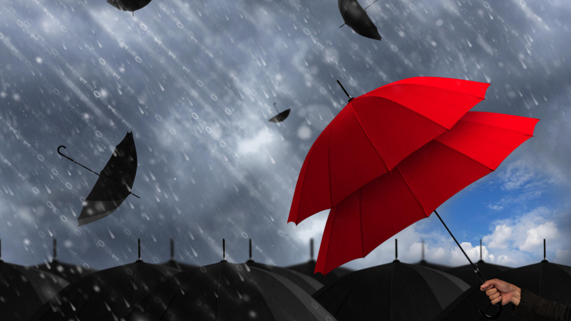 Eine Person hält einen leuchtend roten Regenschirm inmitten vieler schwarzer Regenschirme im strömenden Regen. Ein starker Wind bläst einige schwarze Regenschirme weg. Der Himmel ist dunkel und bewölkt, aber ein blauer Fleck ist sichtbar.