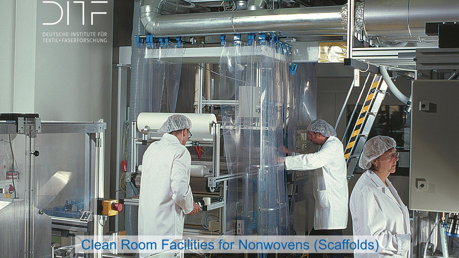 Three people in lab coats, hairnets, and masks work with machinery in a clean room filled with industrial equipment and clear plastic curtains. Text reads: “Clean Room Facilities for Nonwovens (Scaffolds).”.