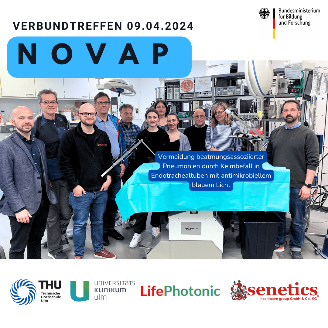 Eine Gruppe von Menschen steht in einem Labor zusammen und hält ein blaues Schild zur Vorbeugung von beatmungsassoziierter Lungenentzündung. Unter der Gruppe erscheinen die Logos von THU, Universitätsklinikum Ulm, Life Photonic und Senetics.