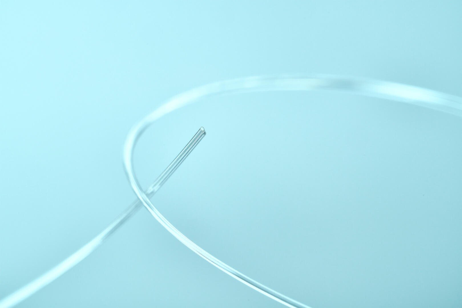 A close-up of two thin, transparent wires or threads intersecting against a light blue background, creating a minimalist and abstract visual effect.