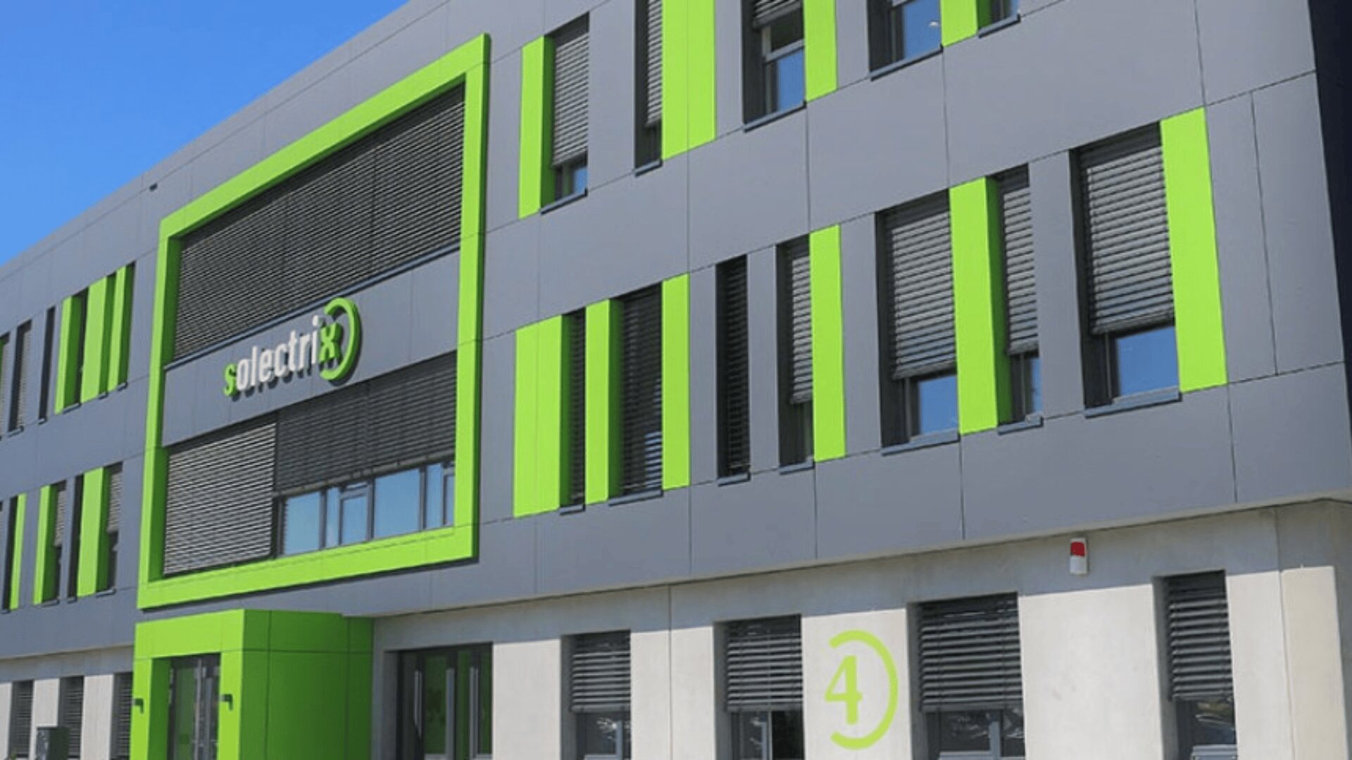 Ein modernes Geschäftsgebäude mit grauen und hellgrünen Paneelen, dem Solectrix-Logo über großen Fenstern und der Nummer 4 in der Nähe des Eingangs.