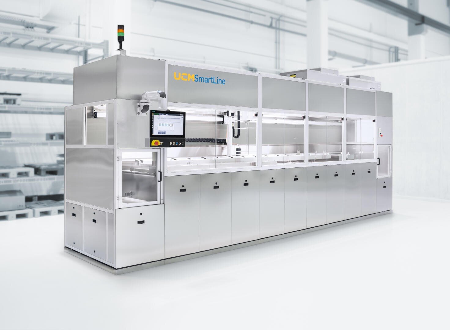 A large industrial washing machine labeled UCM SmartLine in a clean, modern, and bright facility, featuring a control panel, multiple glass windows, and a stainless steel exterior.