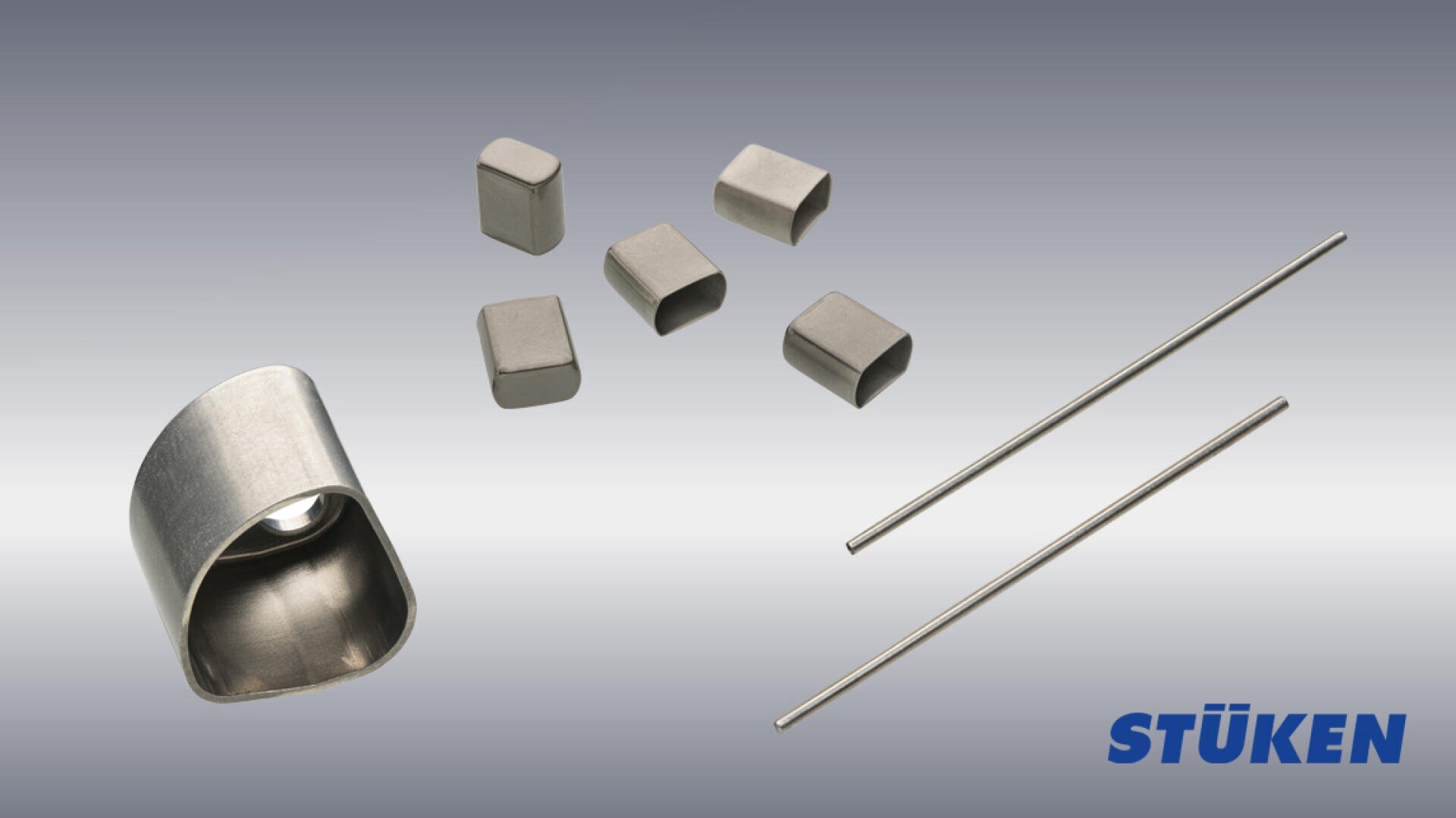 Six small metallic components and two thin rods are arranged on a gradient gray background, with the blue STÜKEN logo in the bottom right corner.