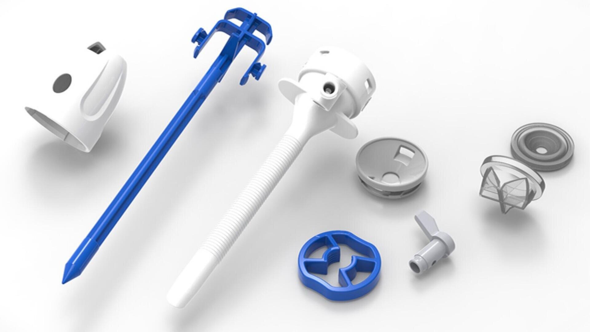 An array of disassembled plastic components, including blue and white rod-like and circular pieces, displayed on a white surface. The parts appear to belong to a medical or mechanical device.
