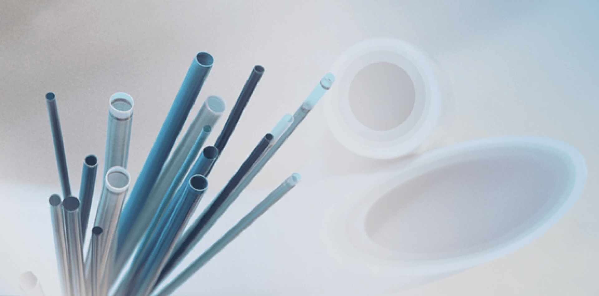 Ein Bündel blauer und weißer durchsichtiger Kunststoffröhren verschiedener Längen und Durchmesser, die diagonal vor einem weichen, hellblauen und weißen Hintergrund mit Farbverlauf angeordnet sind.