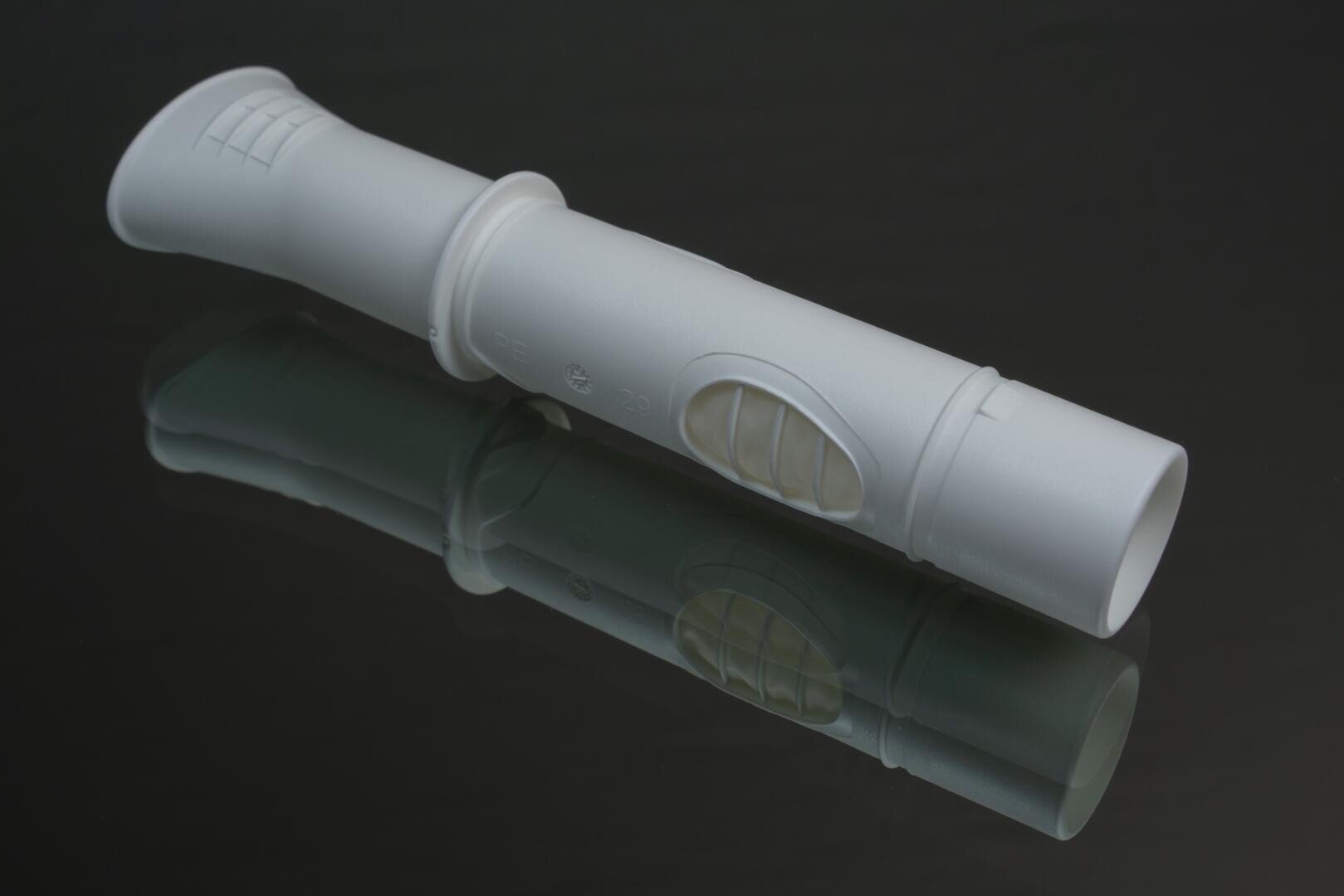 Eine weiße Kunststoffblockflöte liegt auf einer reflektierenden schwarzen Oberfläche, die ihre Grifflöcher und ihr Mundstück zeigt. Durch die Reflexion entsteht ein Spiegeleffekt unter dem Instrument.