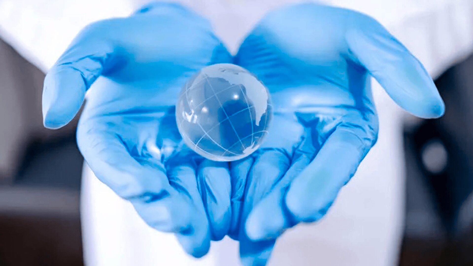 Eine Person mit blauen medizinischen Handschuhen hält sanft einen kleinen, durchsichtigen Globus mit schwachen Kartenlinien, die globale Pflege oder medizinische Verantwortung symbolisieren.