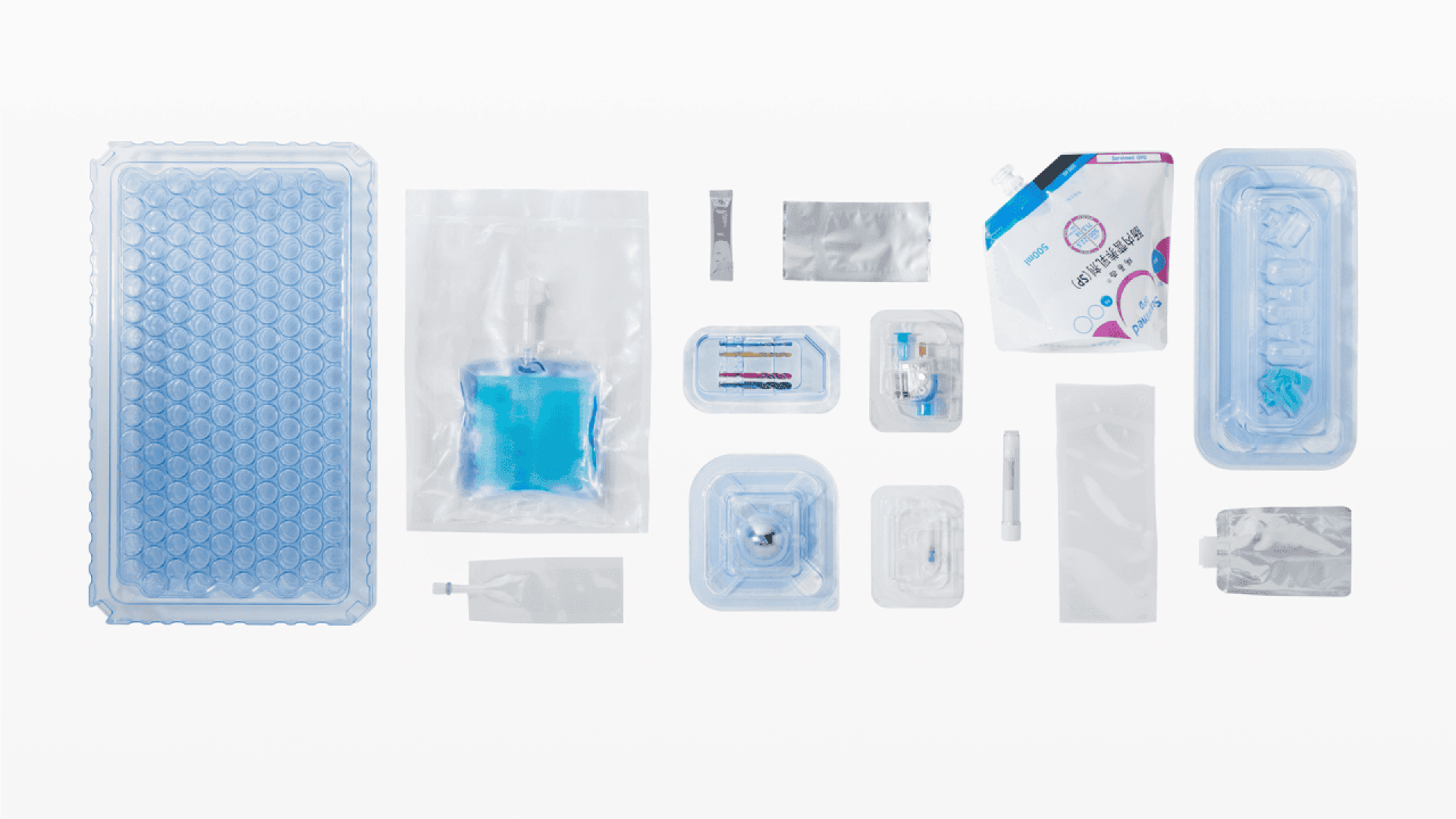 A variety of sterilized medical supplies in clear, blue, and silver packaging are arranged neatly on a white background, including trays, pouches, syringes, and packets.