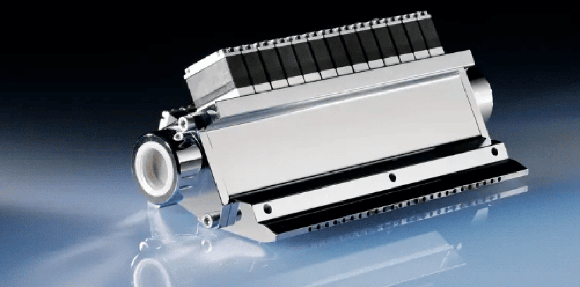 Close-up of a metallic industrial printhead with a slim, rectangular design, multiple black nozzles at the tip, and a shiny, reflective surface, presented on a glossy blue background.