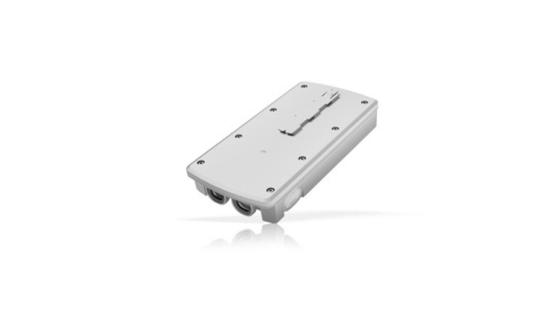 A rectangular, white electronic device with rounded edges, multiple screws on its surface, two visible cable ports, and a worn or scratched area on the top.