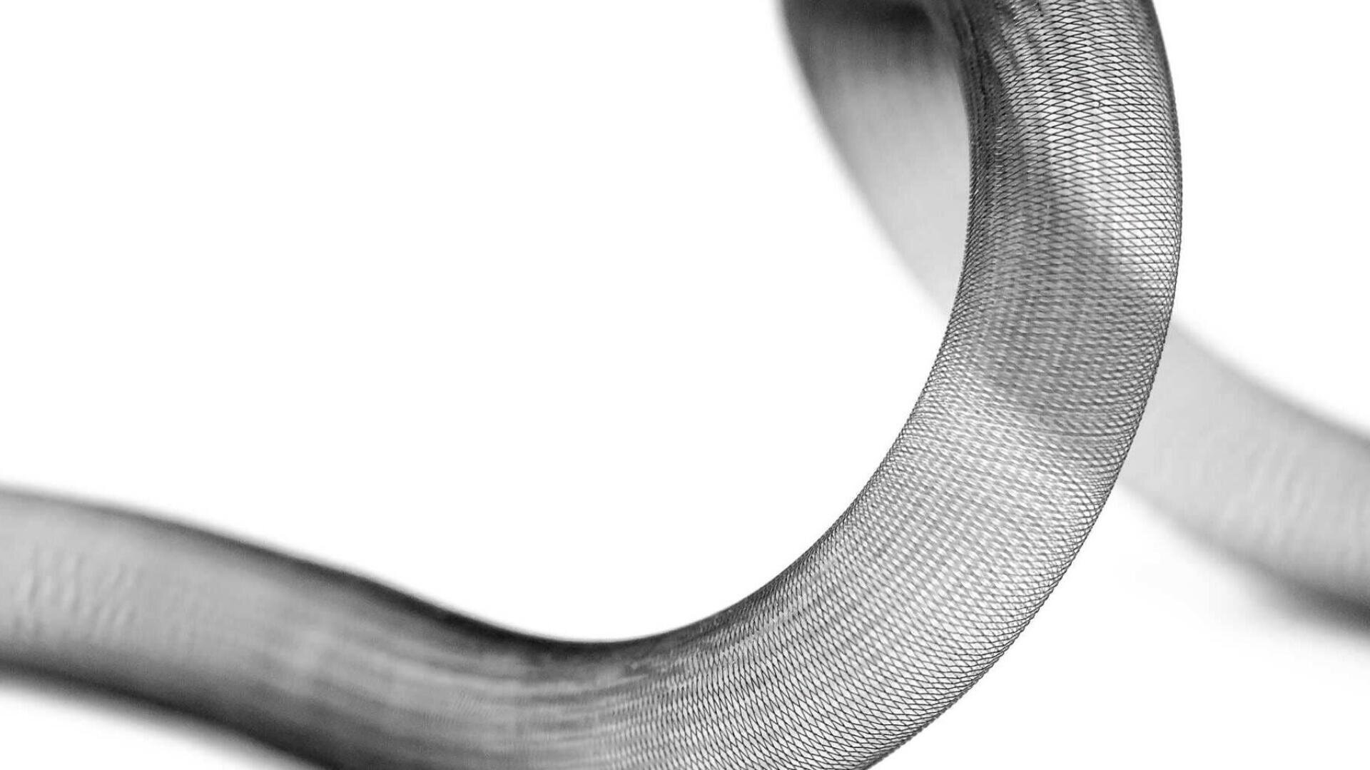 Nahaufnahme eines biegsamen, gebogenen Metallgeweberohrs vor weißem Hintergrund, das eine fein gewebte Textur und glatte, fließende Linien zeigt.